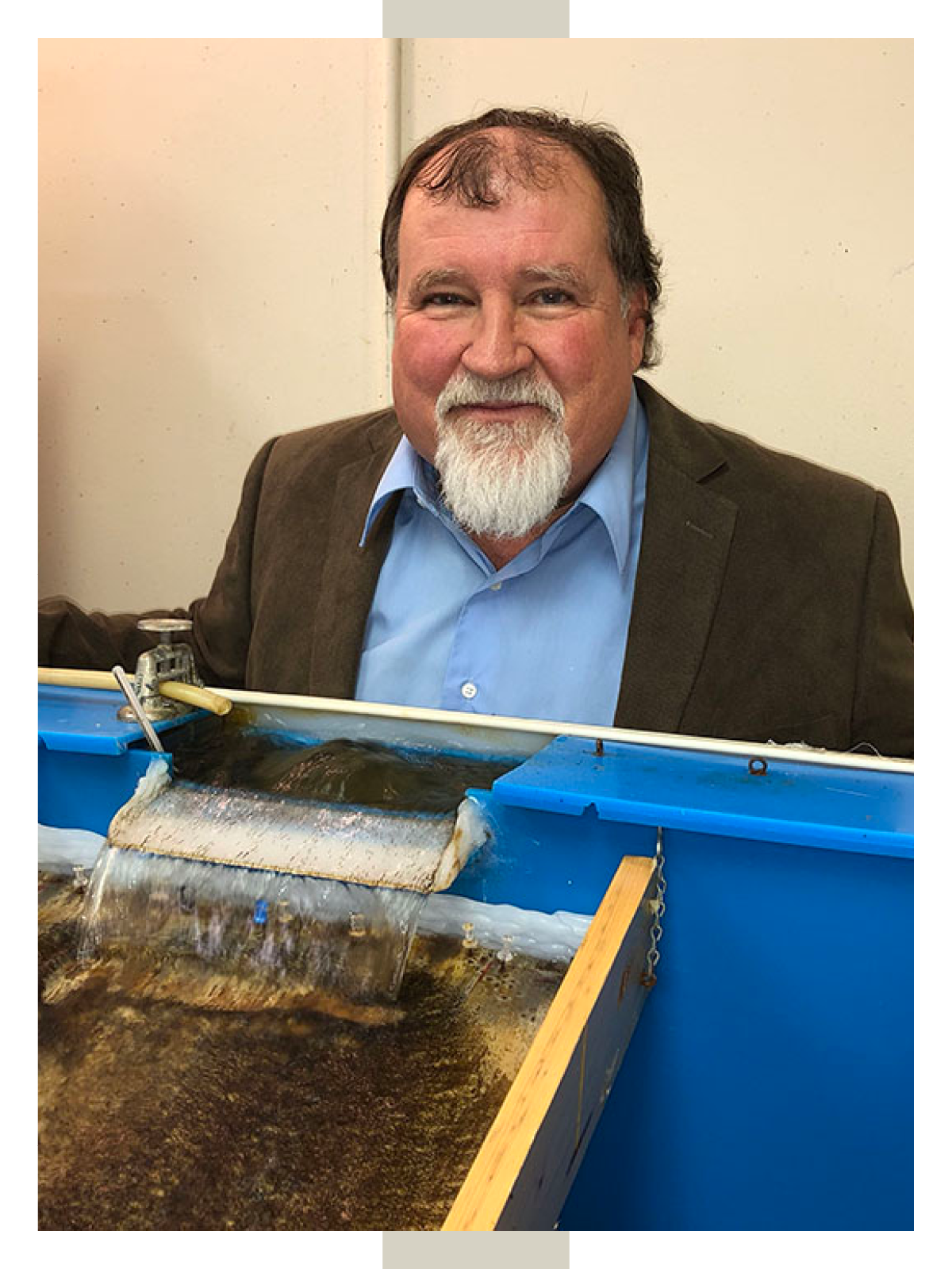 Elmer poses for a photo in the black fly lab in front of a simulated creek