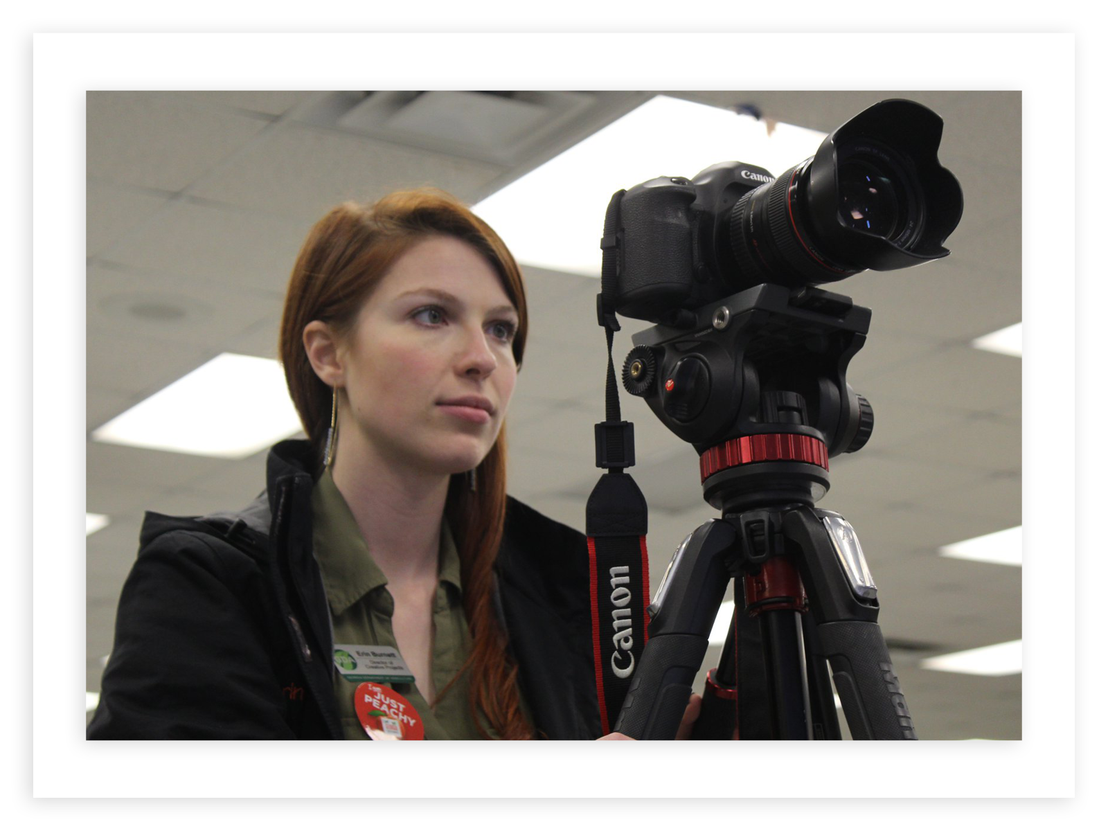 A woman operates a digital video camera on a tripod.