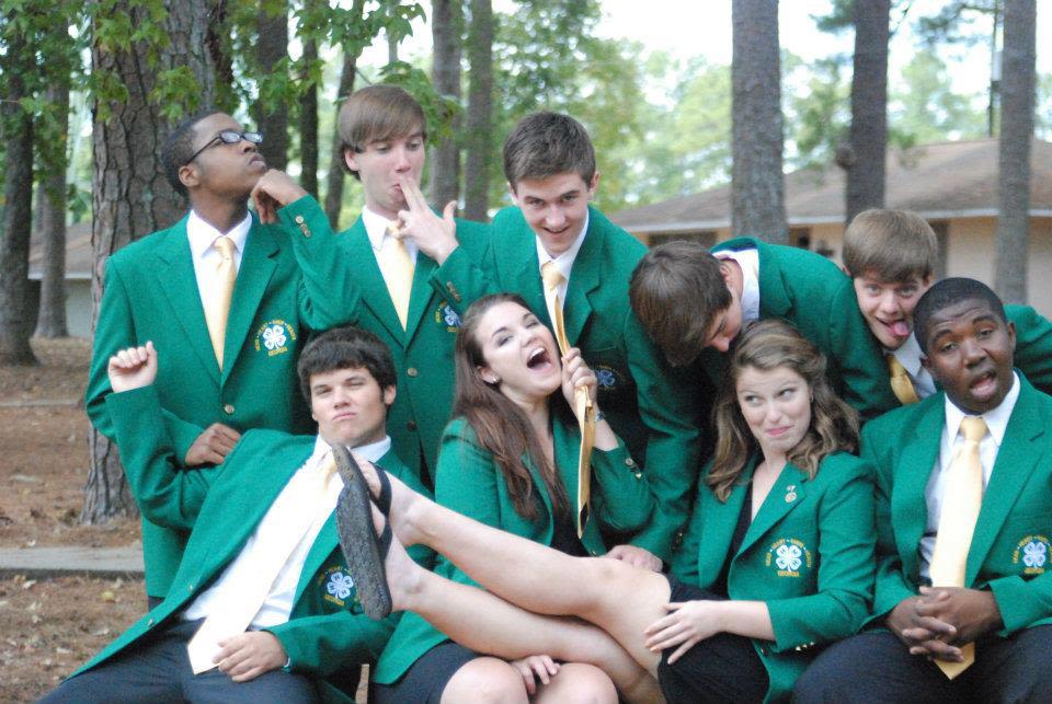Nine 4-H campers pose for a silly photo wearing their green blazers
