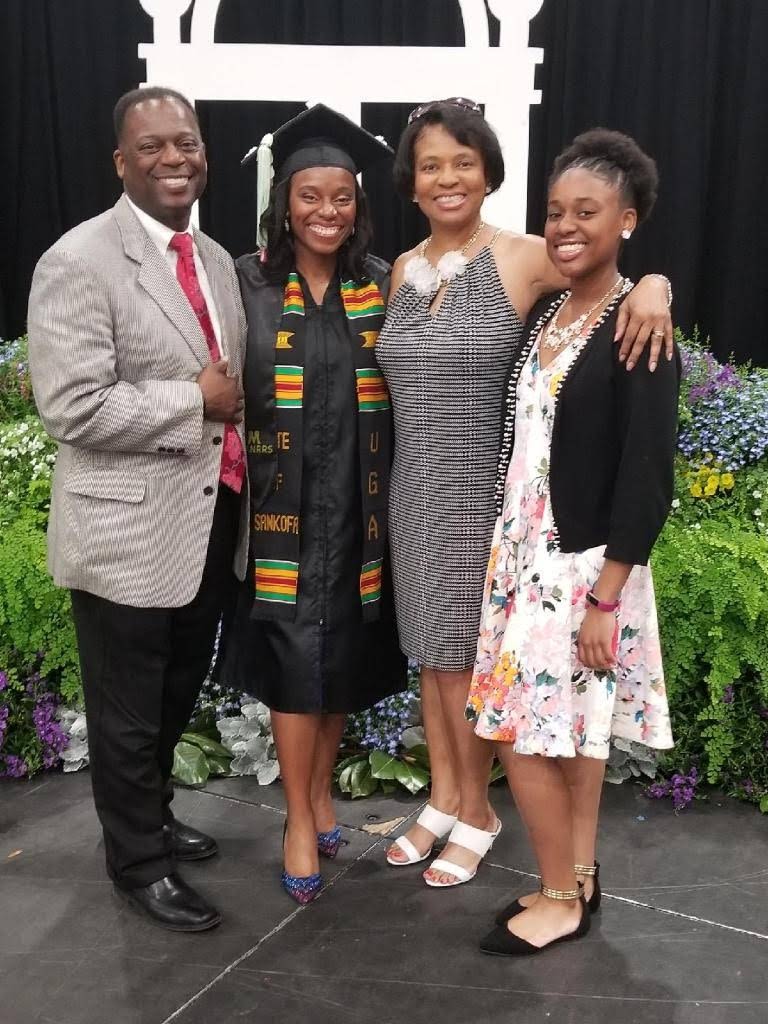 Thomas' family poses for a photo in front of a display on the graduation stage