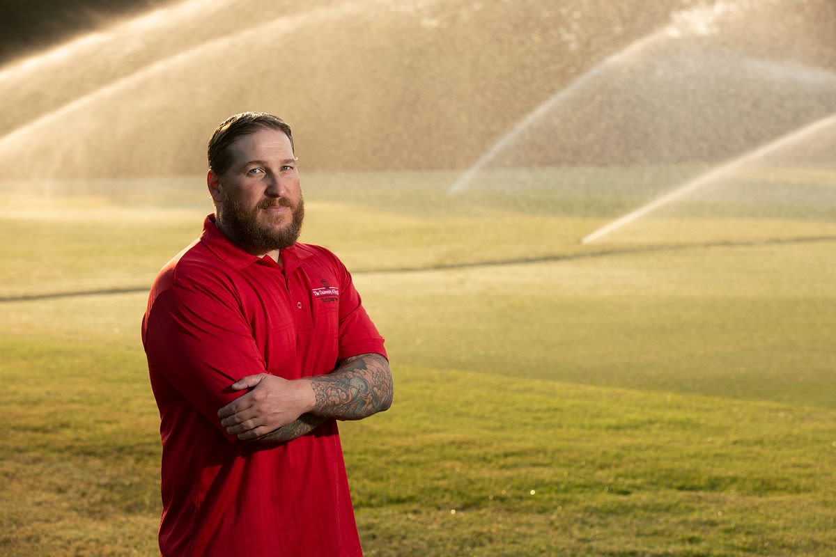 Gerald stands in a turfgrass field with sprinklers running behind him