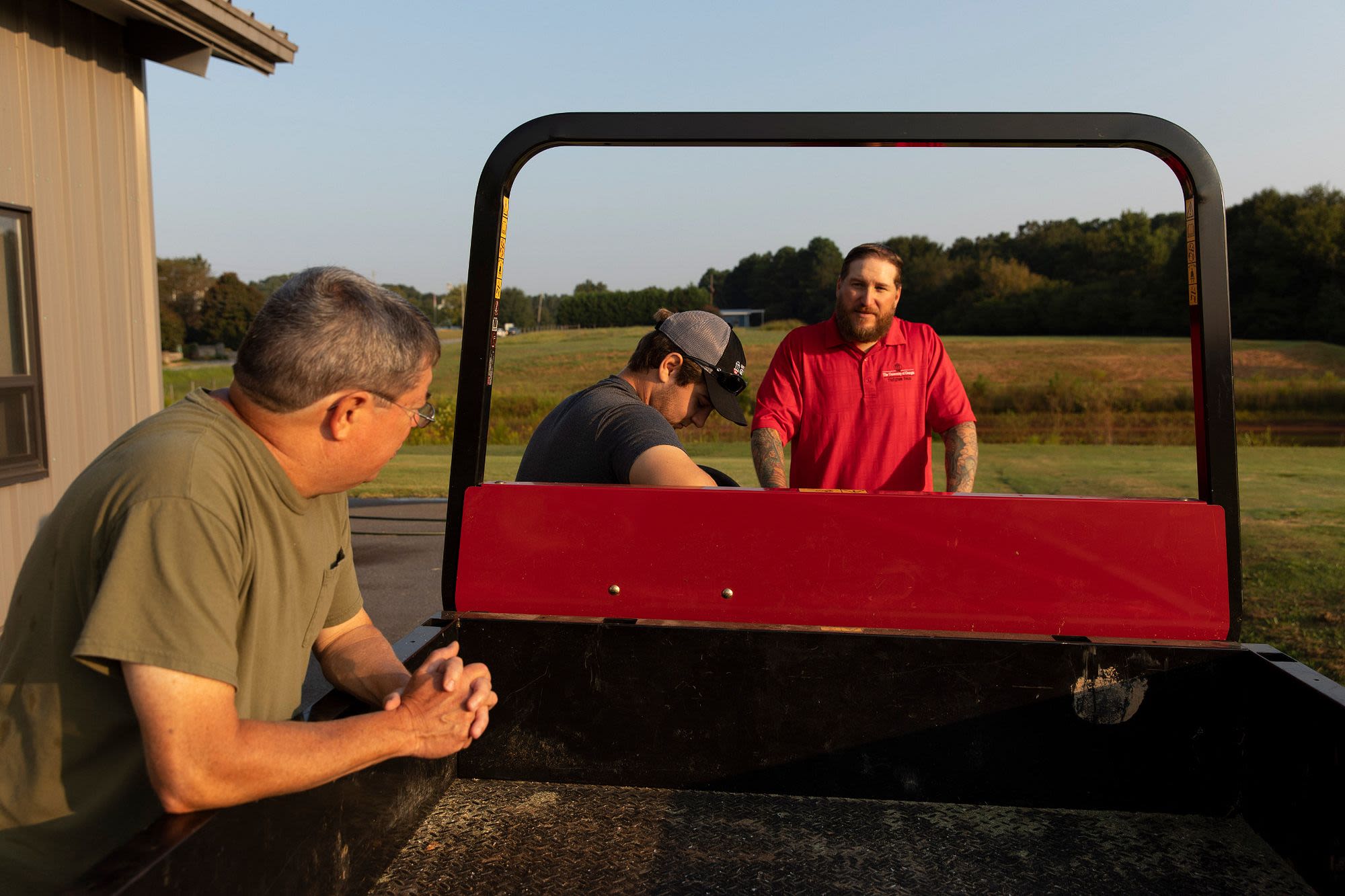 Three men chat while standing around an ATV