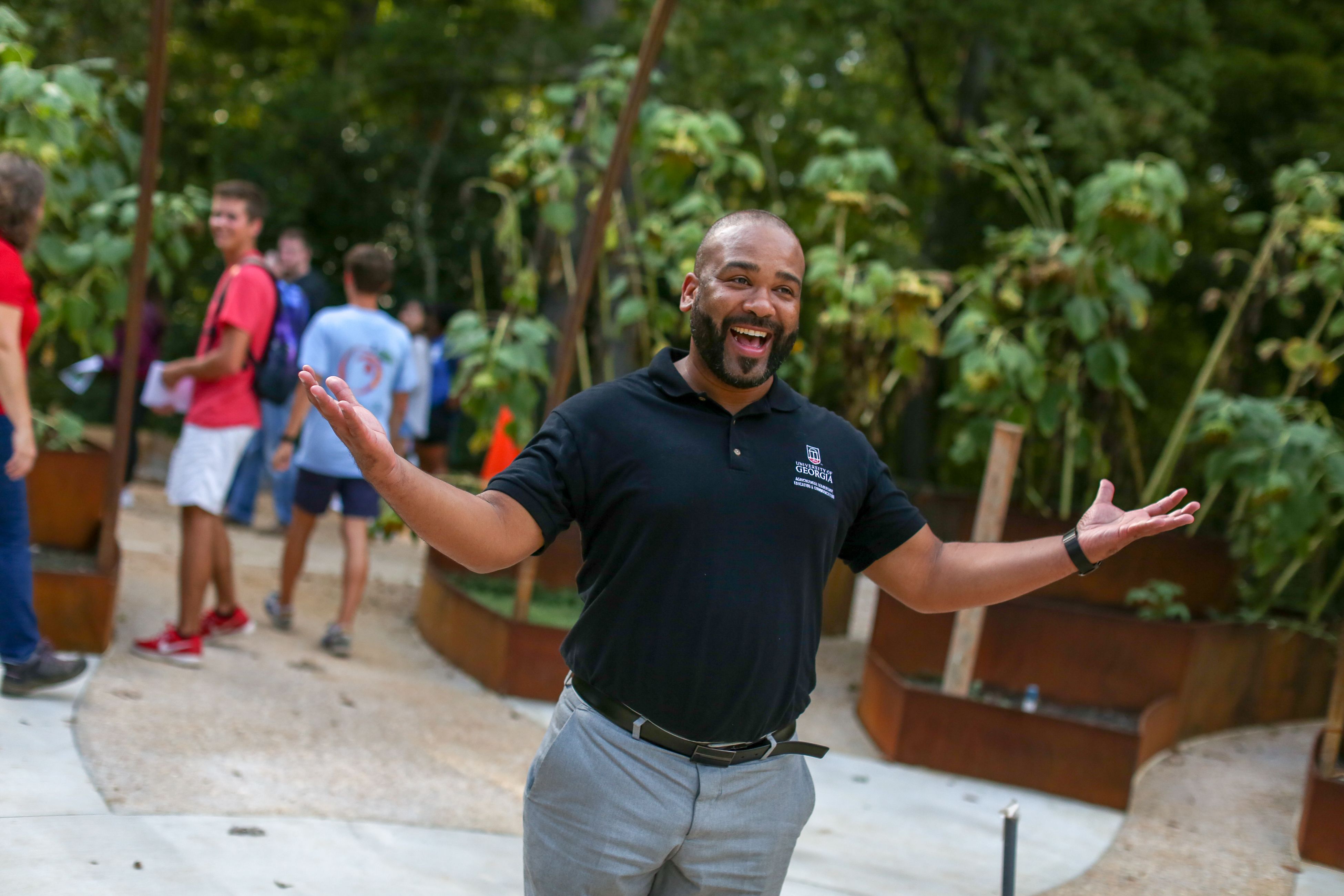 Man lifts arms and smiles in park garden