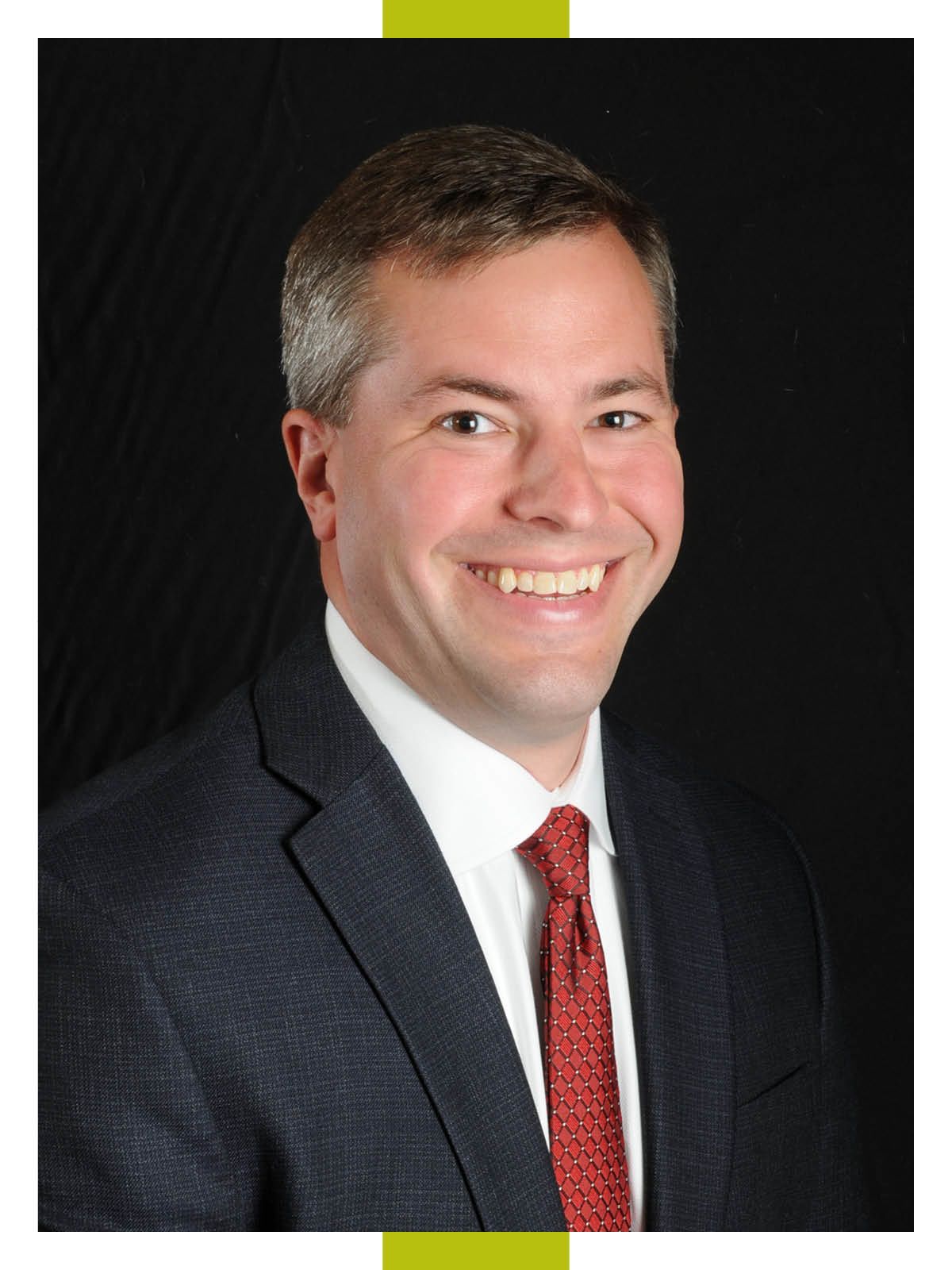 Headshot of CEO in a sports jacket and a red tie.