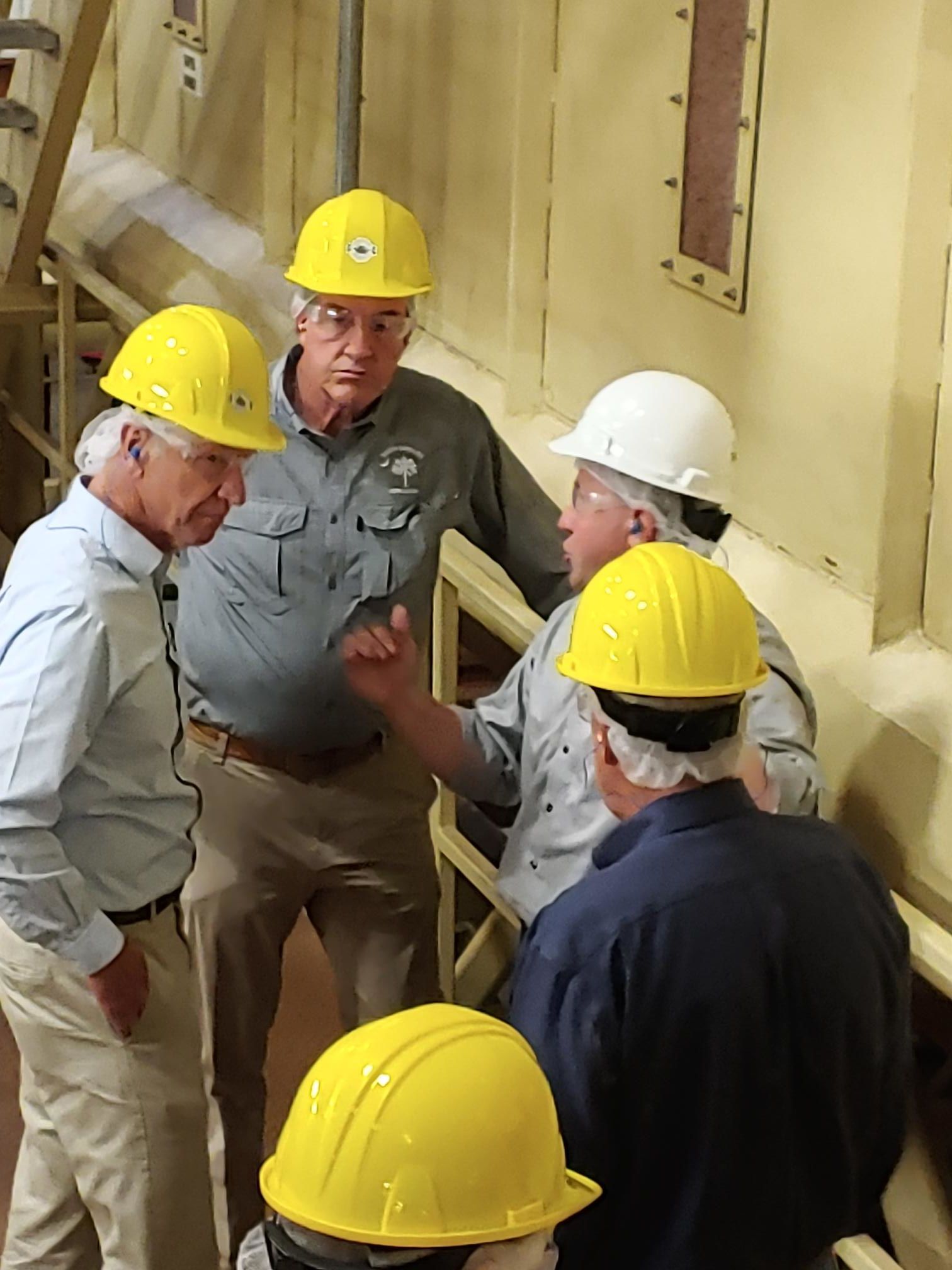 Five businessmen in hard hats having a serious discussion.