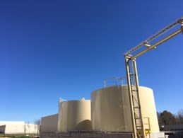 Landscape of a peanut warehouse with two tall cylindrical buildings against a bright blue sky.