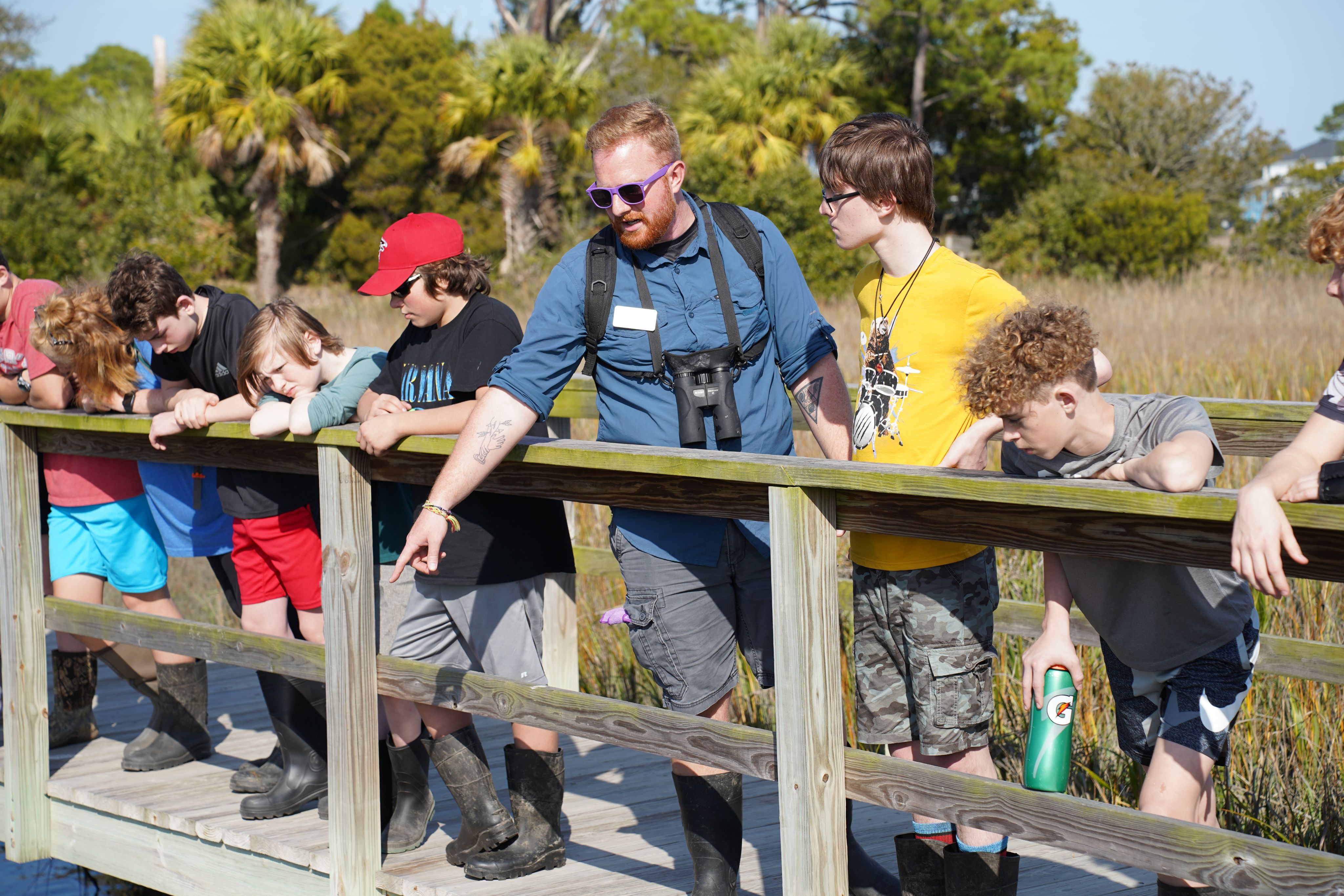 Gorgas points out wildlife to young students on a wooden boardwalk at the Burton 4-H Center