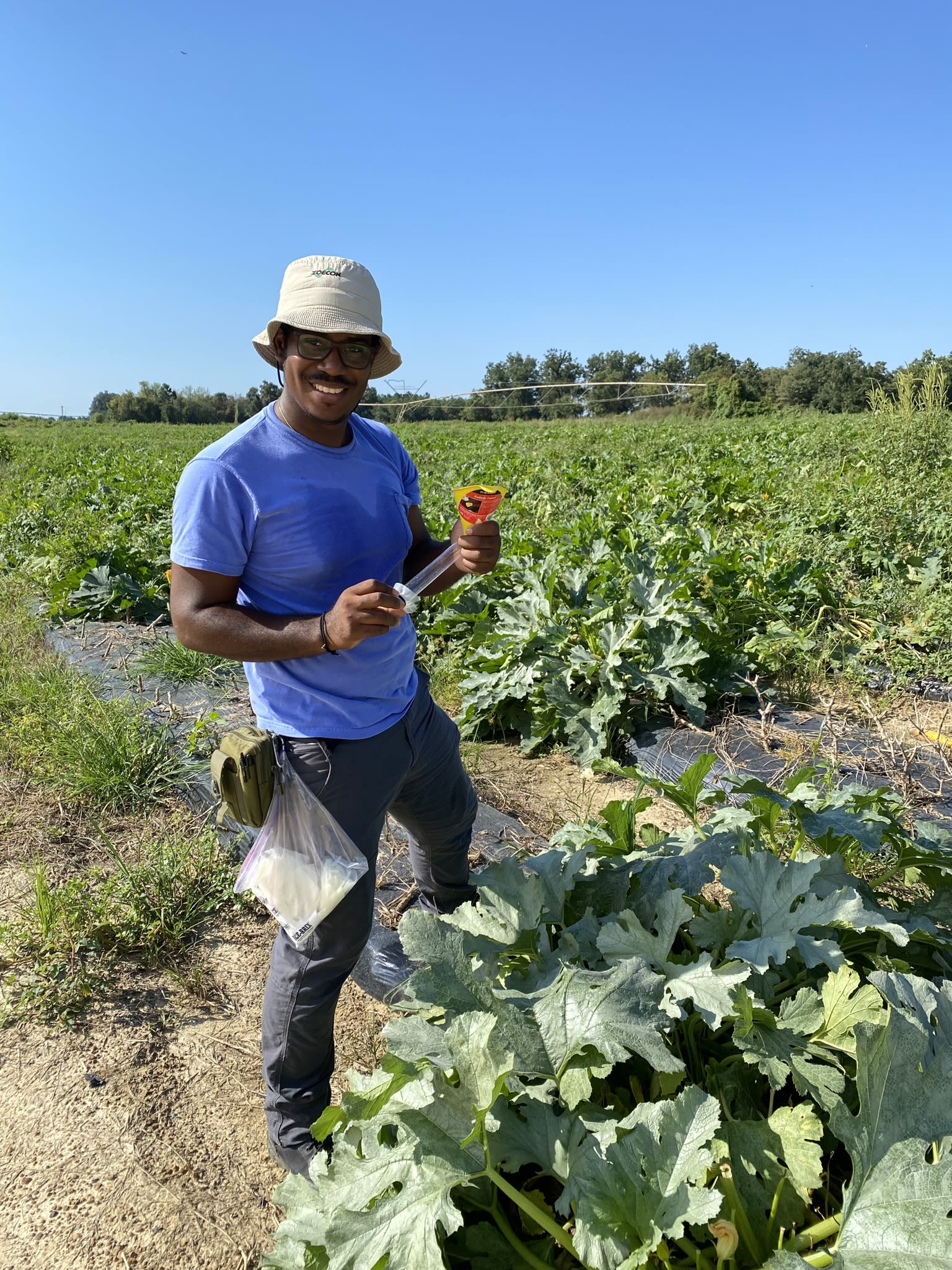 Perier holds a funnel and survey equipment in a field