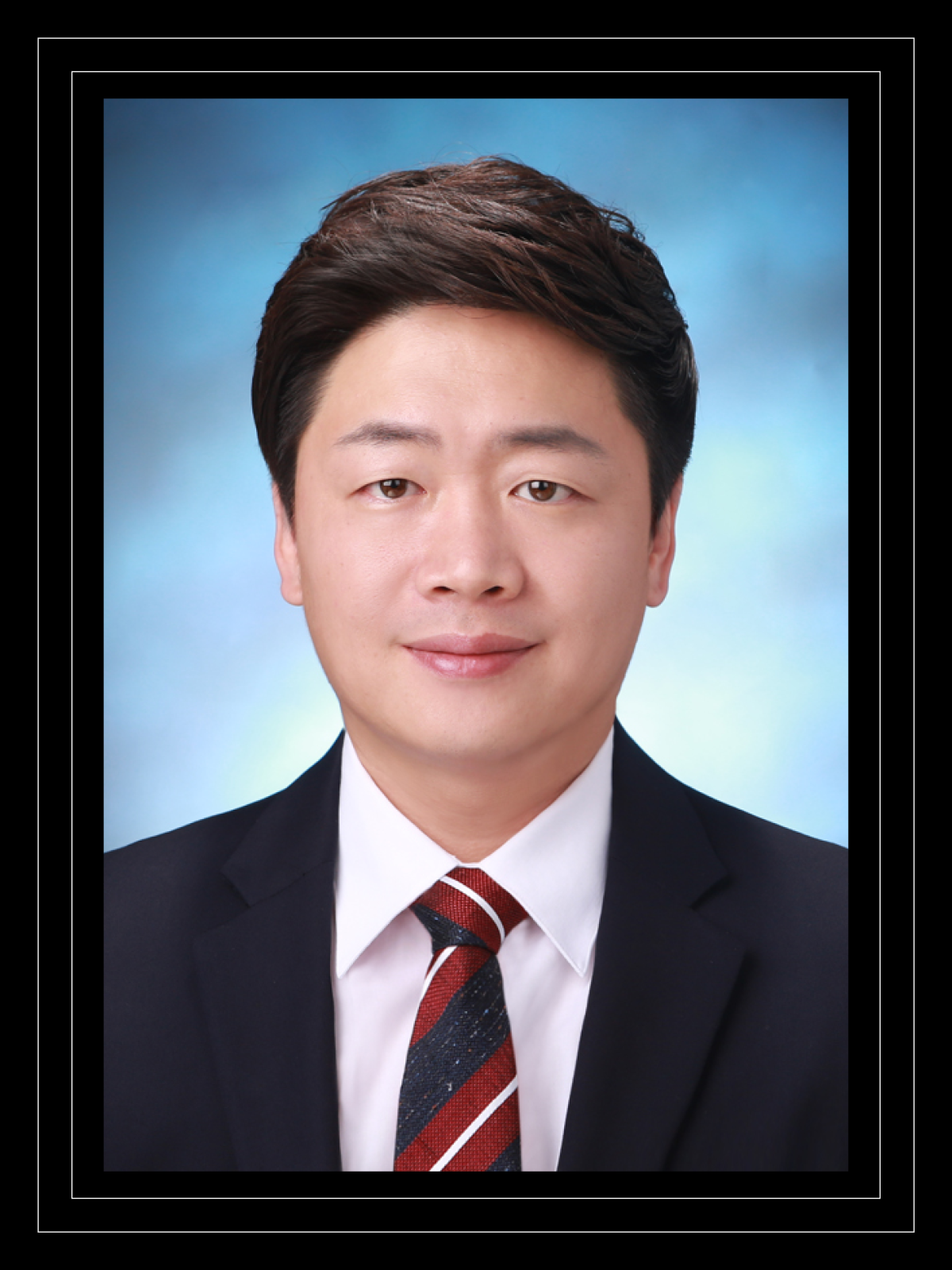 Jongyum Kim in a suit against a blue background in his professional headshot