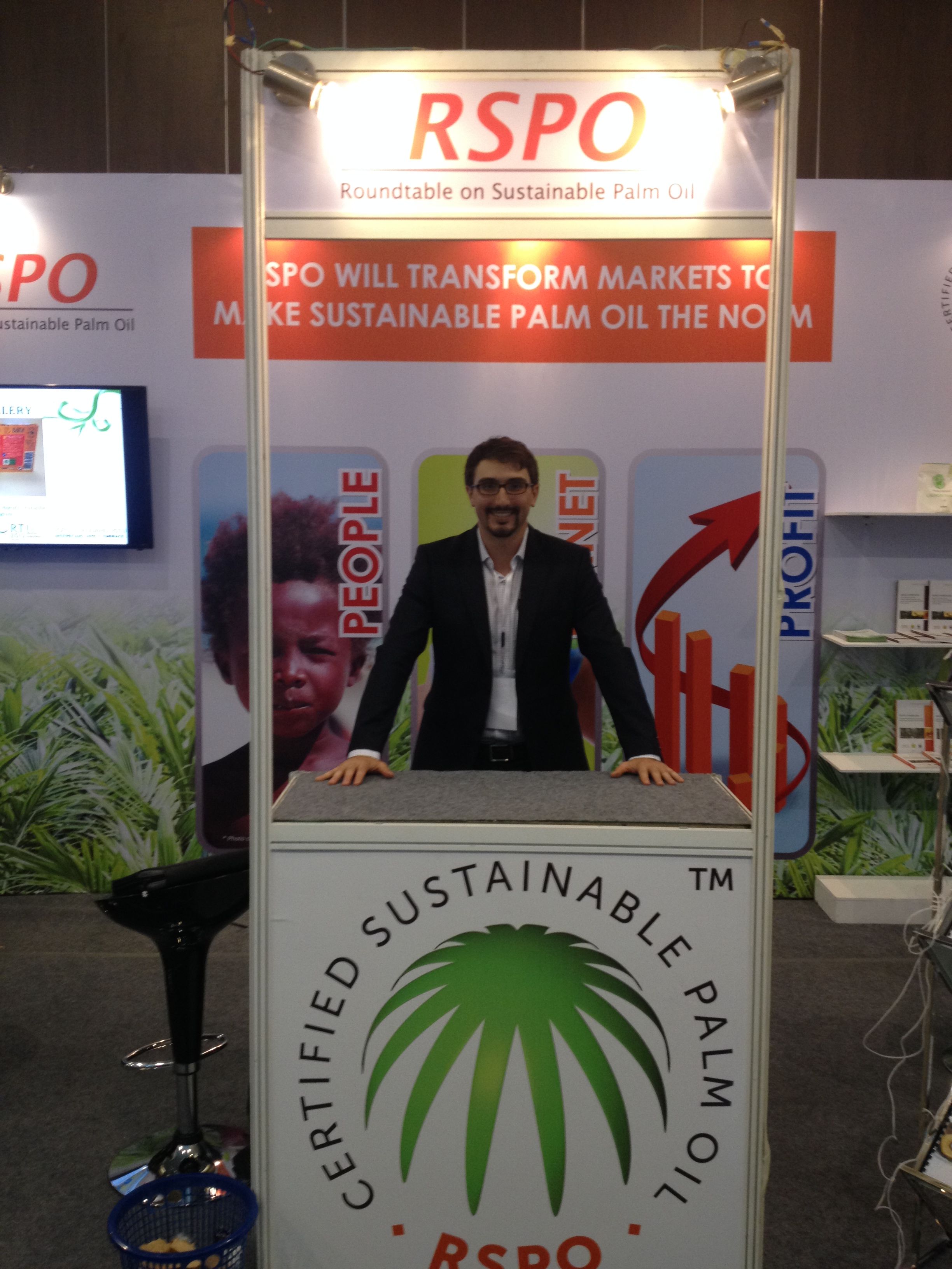Lee Gross stands at a booth that reads "Certified Sustainable Palm Oil" at a conference.