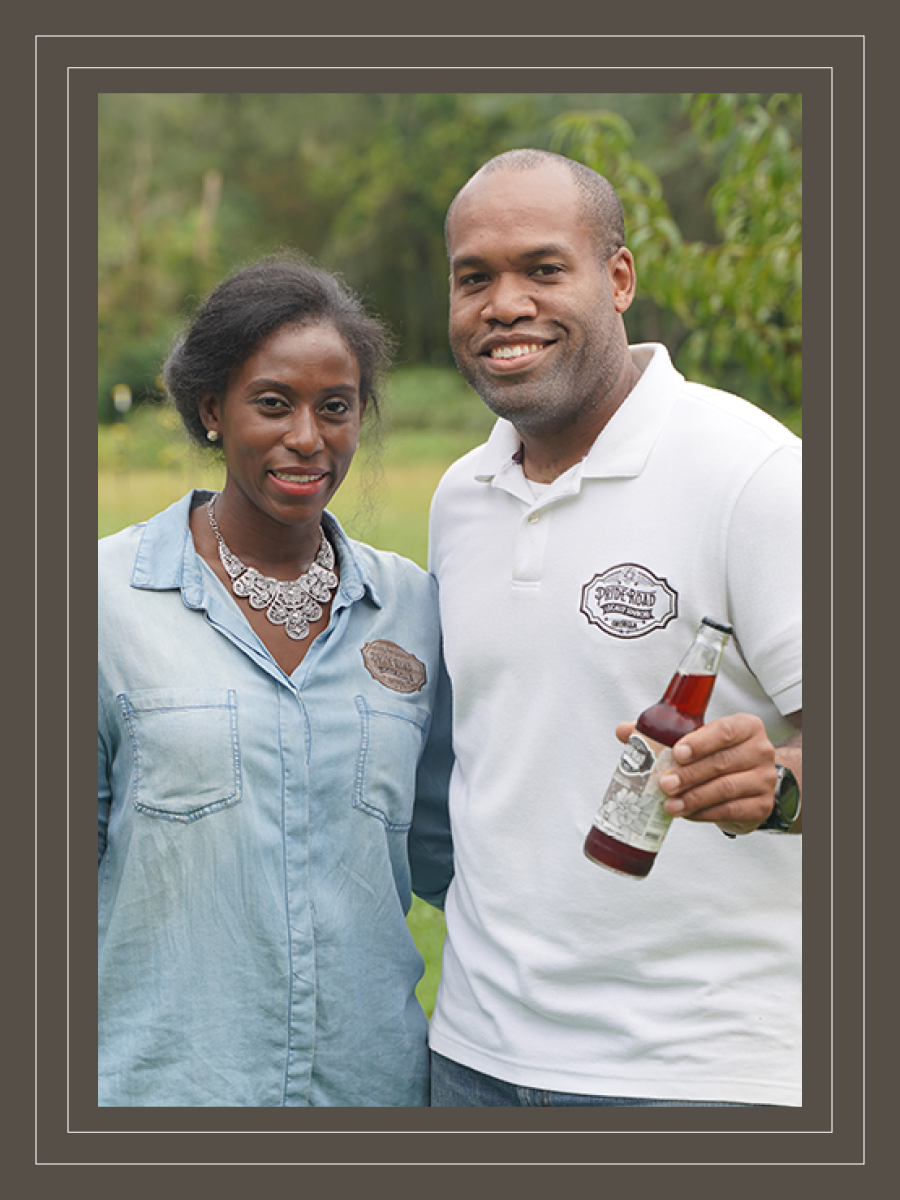 A woman and man pose for a photo with a bottle of hibiscus tea