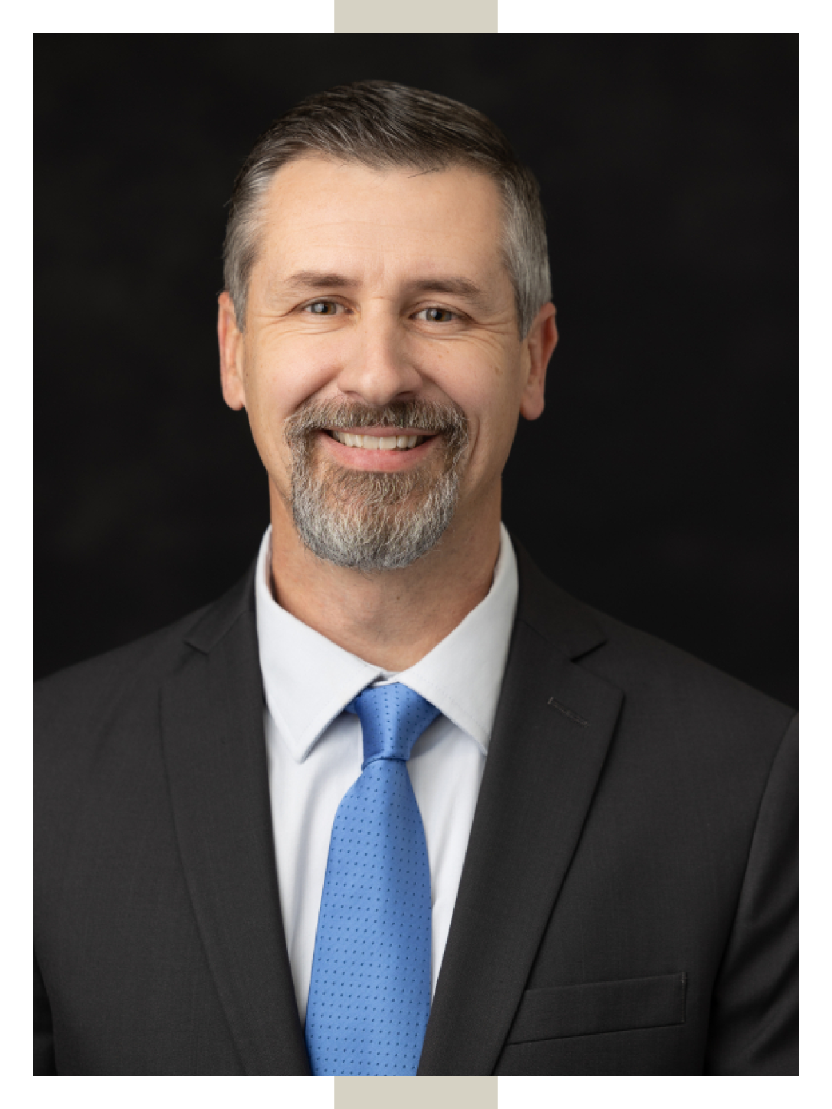 Associate Professor R. Scott Tubbs smiles while wearing a black suit coat, white shirt and blue tie. 