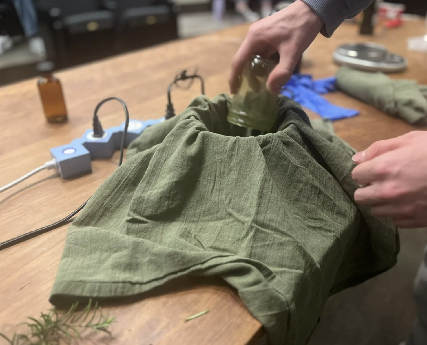 A student pours ground rosemary into olive oil to make rosemary-infused olive oil.
