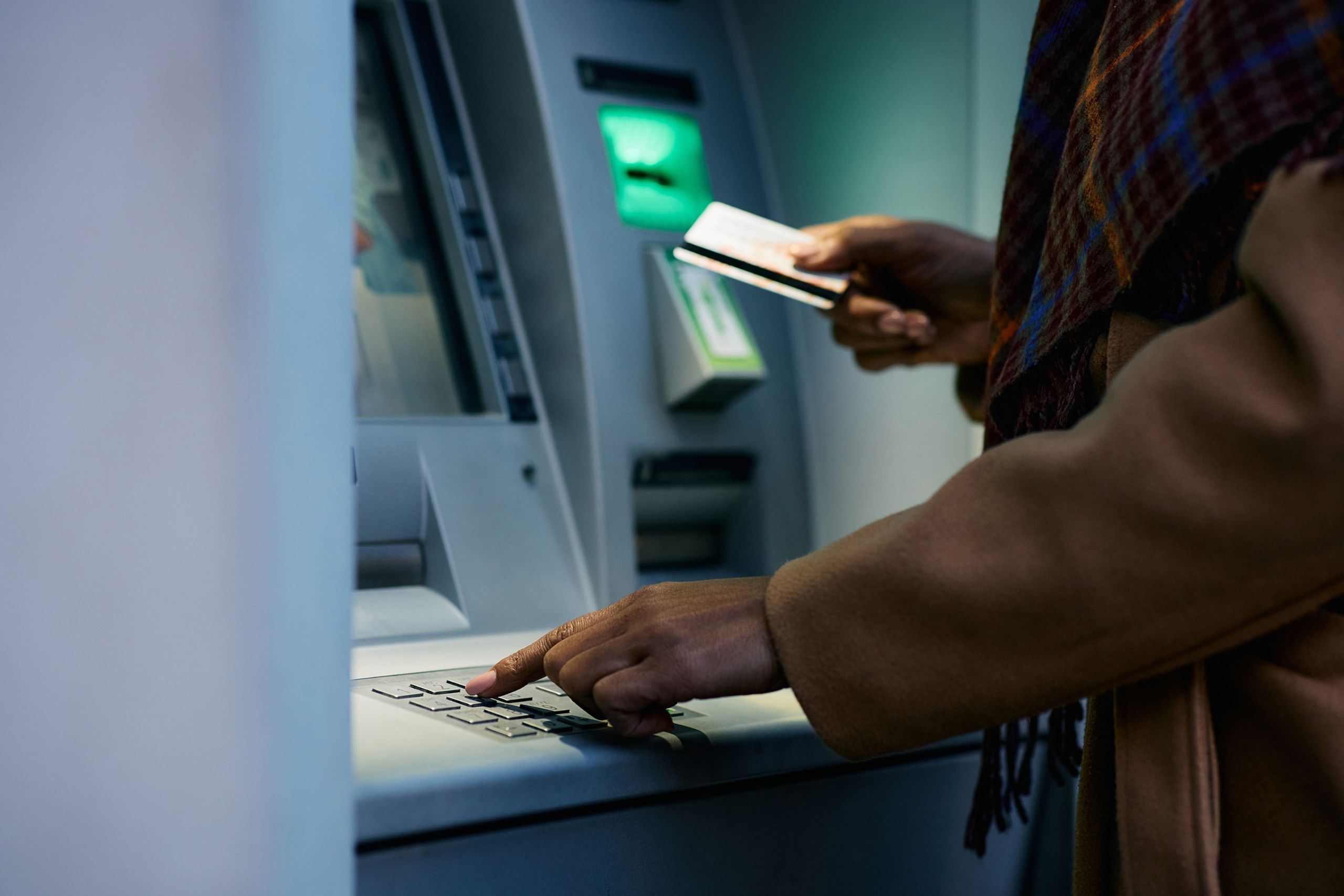 A person is entering a PIN into an ATM machine.