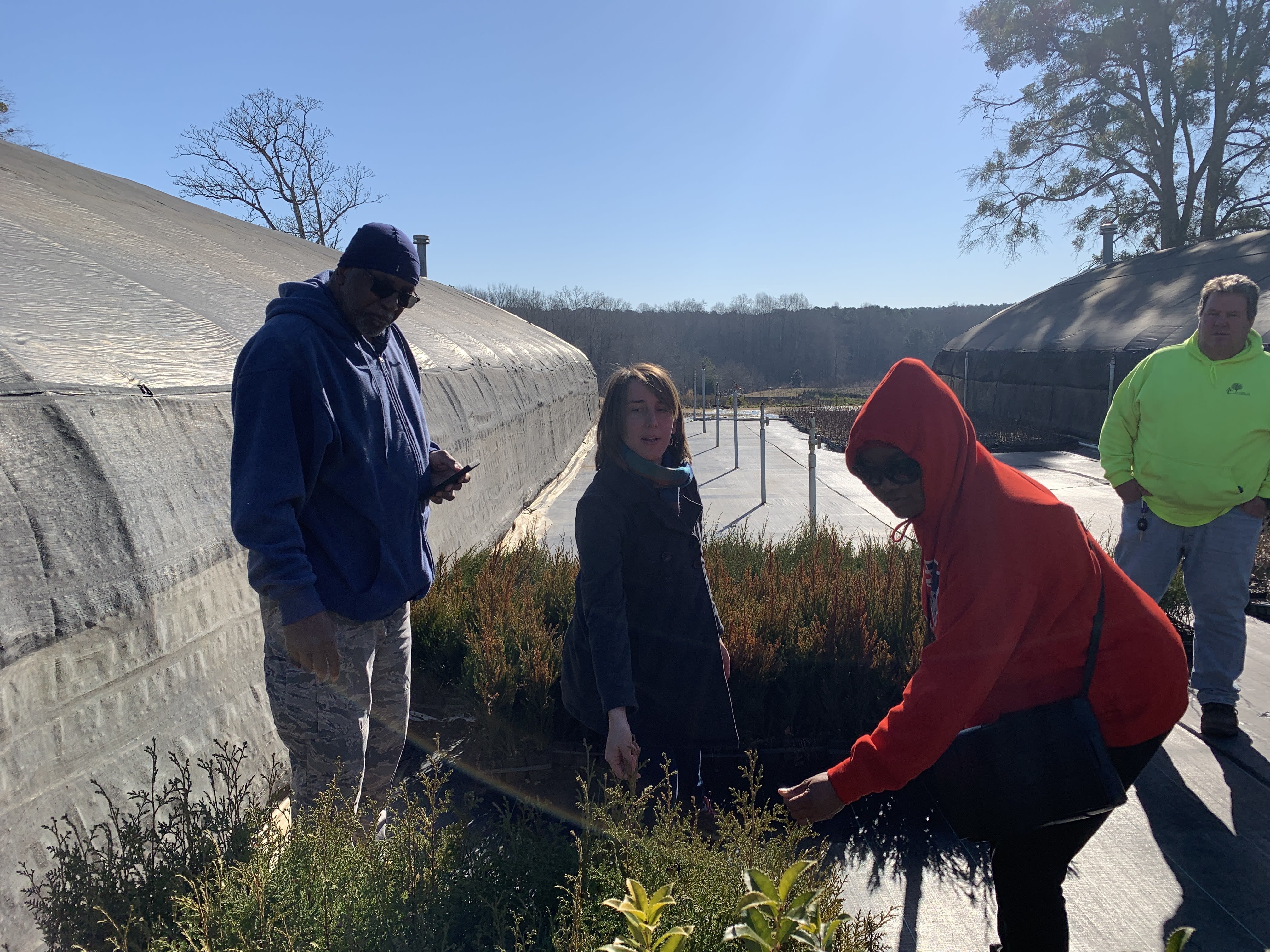 Ney and participants of a Landscape Industry Fundamentals Training look at plants between large growing tunnels