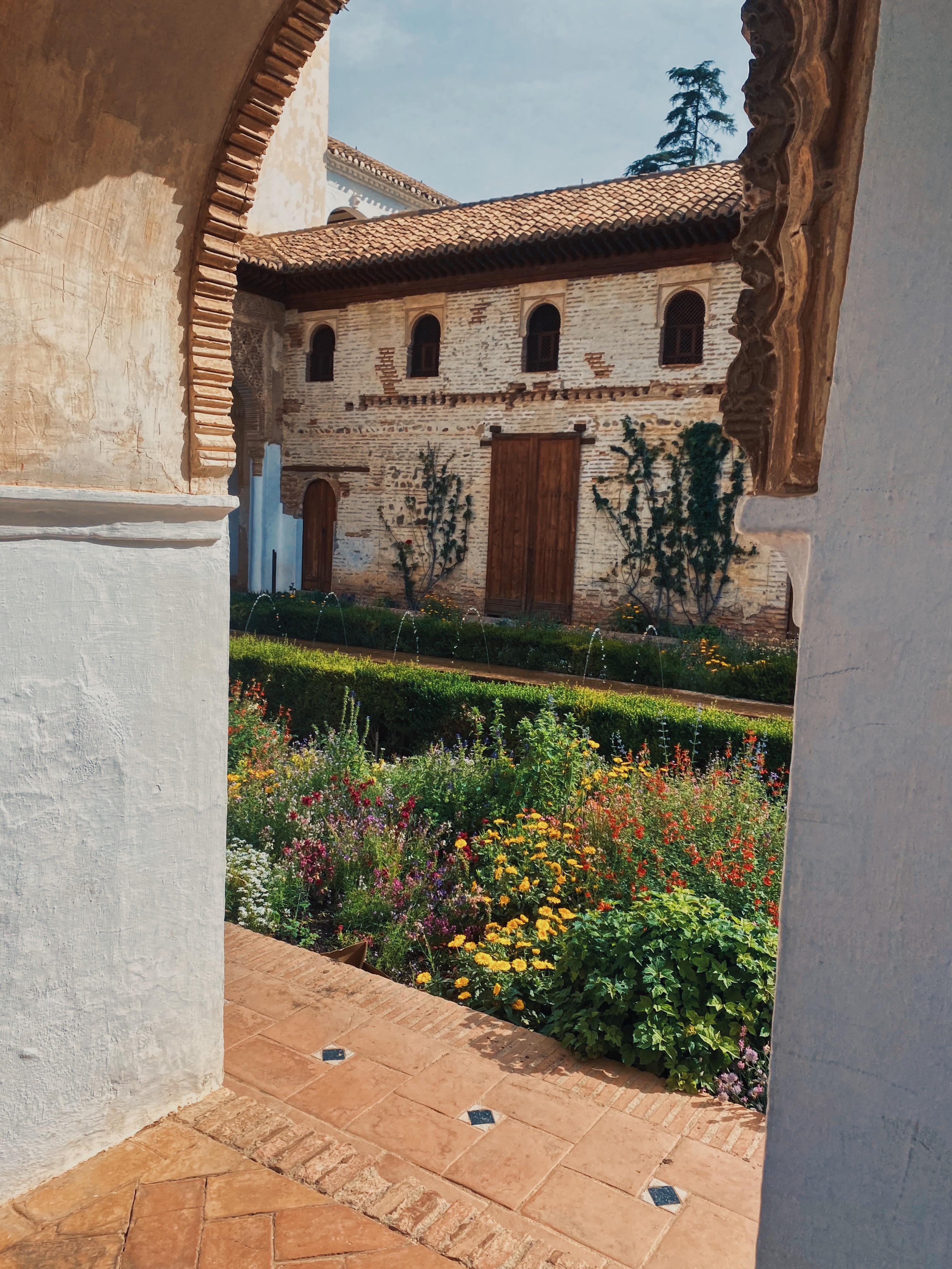 Looking through an arched passageway, a courtyard is in full bloom at a villa in Granada, Spain