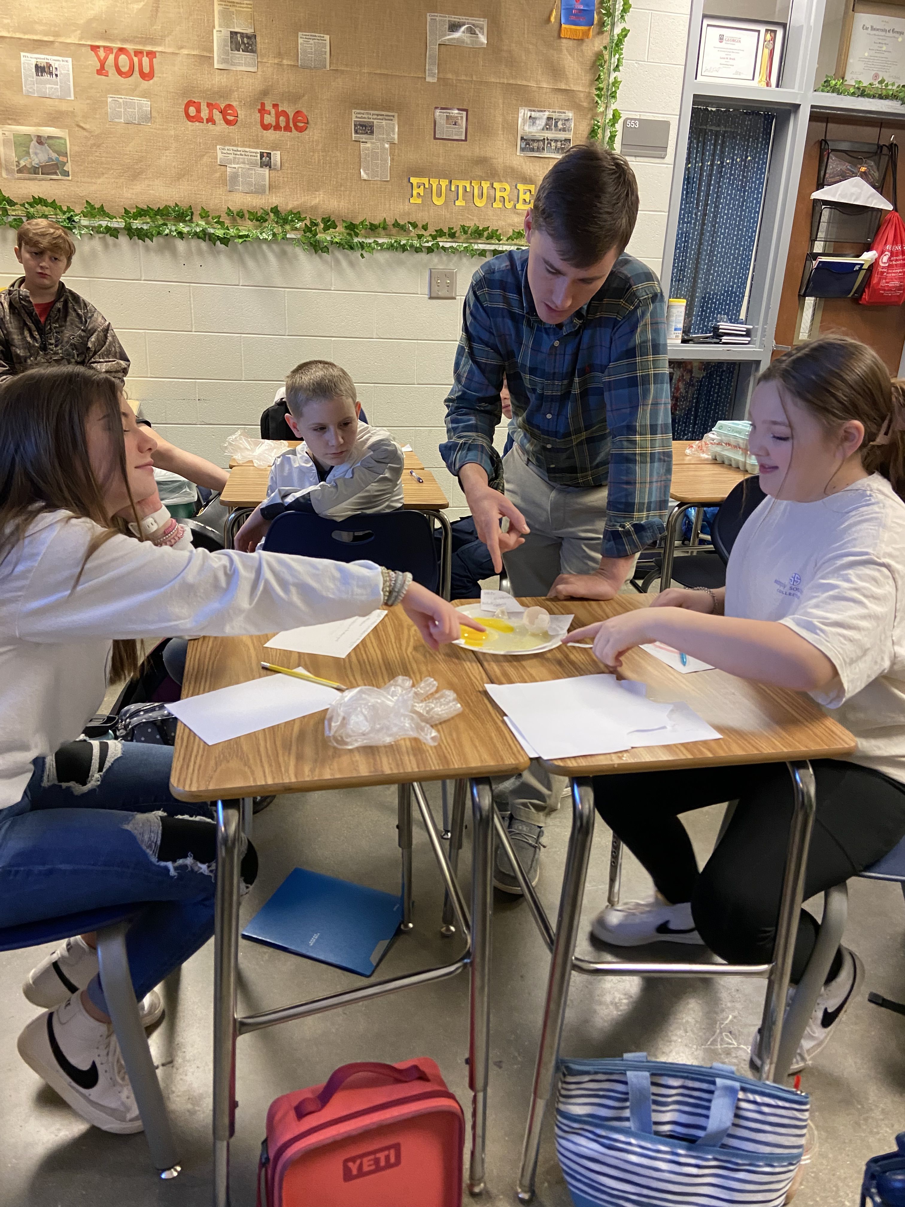 Lucas Brock instructs a small group of students in a classroom setting.