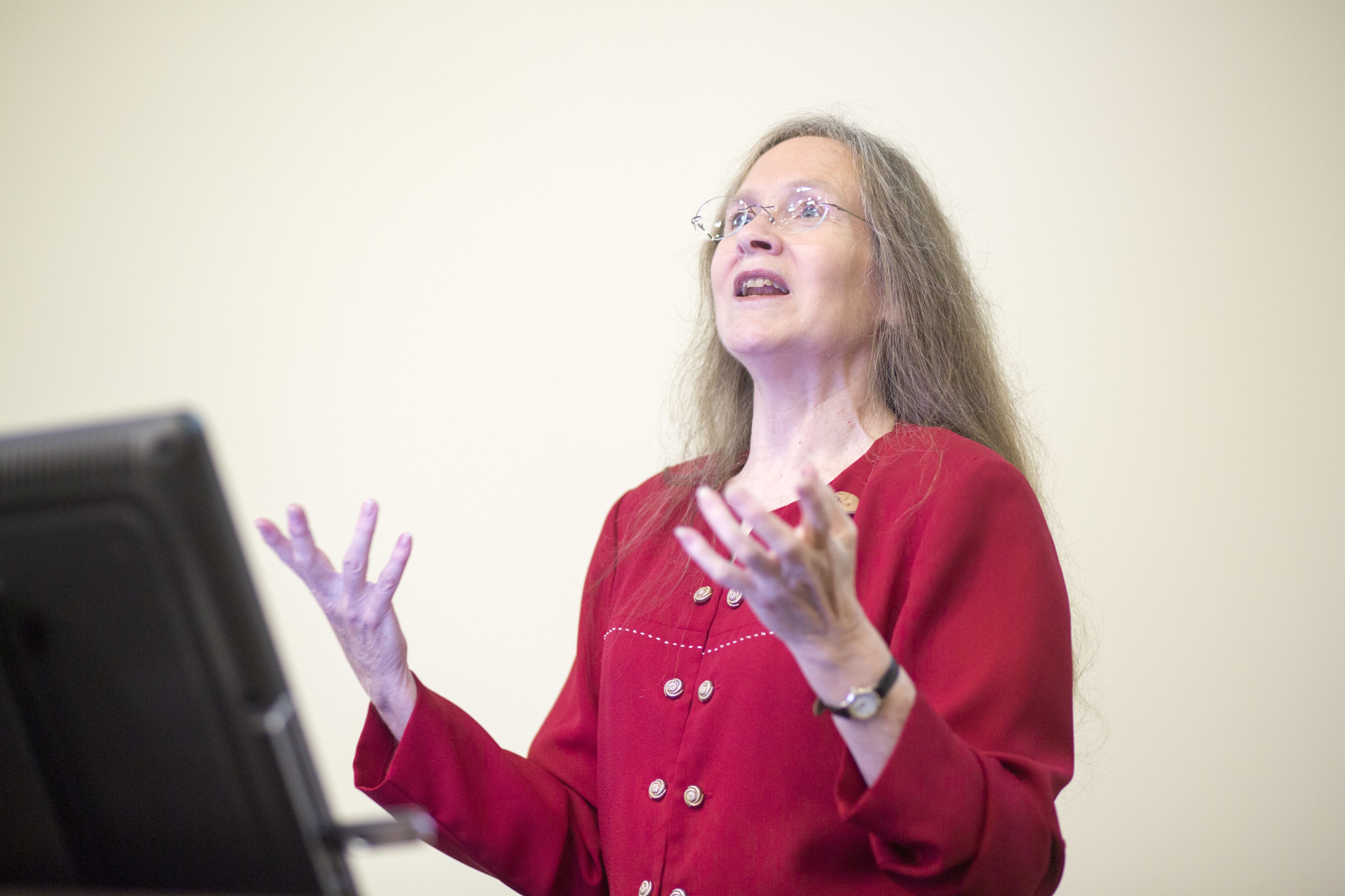 Nancy Hinkle gesticulates in front of her class while teaching behind a computer on alectern.