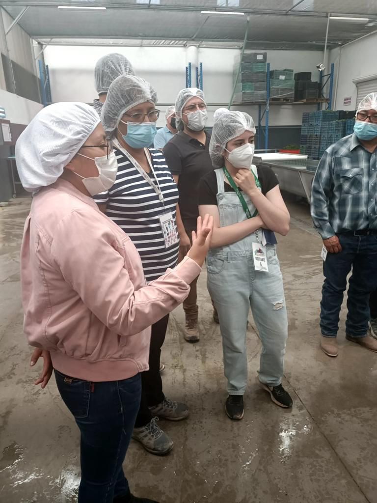 Raad and her colleagues talk while wearing PPE in a produce-packing facility