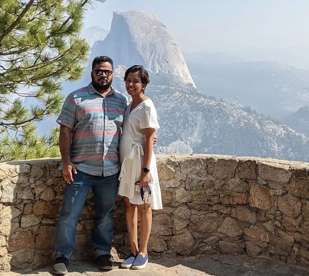 Narwankar (right) posing with her fiancé on an overlook with a huge rock formation in the background