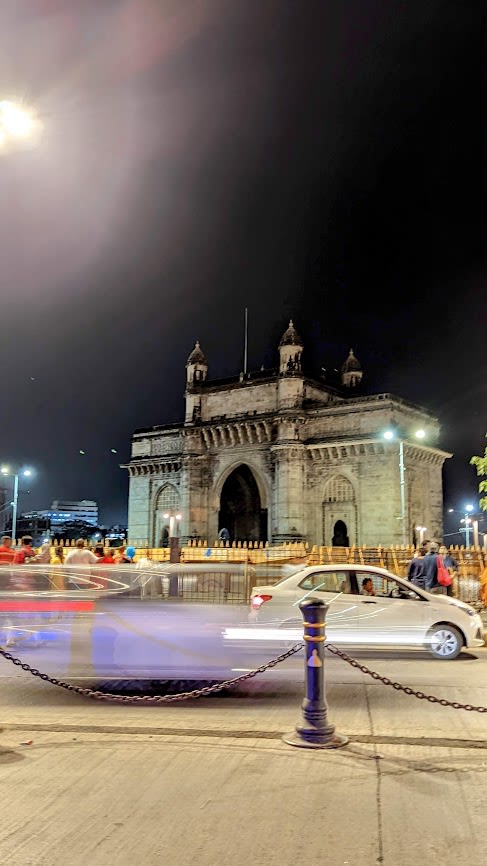 Gateway Mumbai at night with pedestrians and vehicles in the foreground