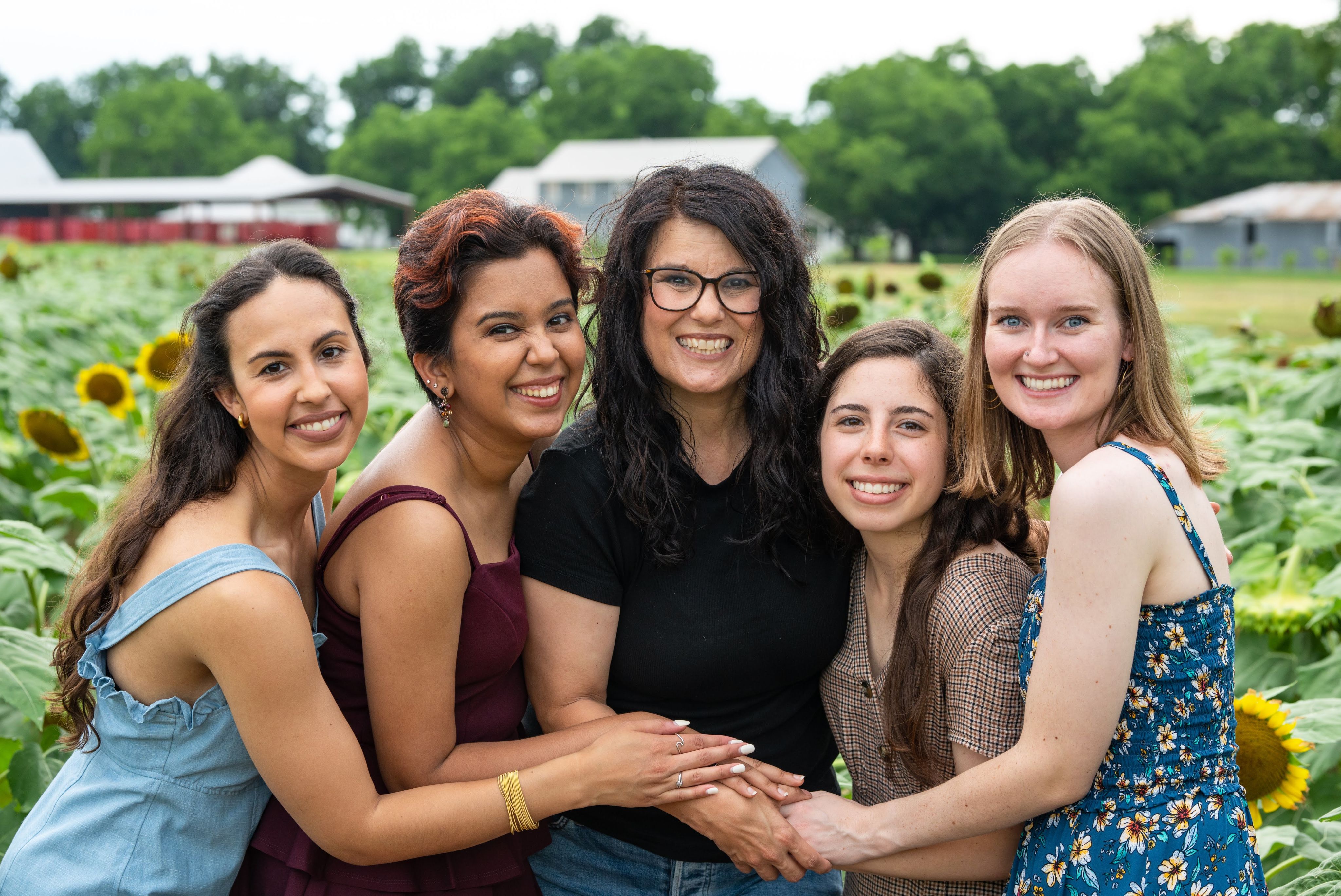 Narwankar, second from left, gathers with four friends in a sunflower field with agricultural buildings in the background