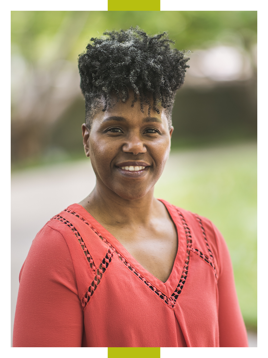 Wearing a red top and with greenery behind her, Shavannor Smith smiles for a head shot