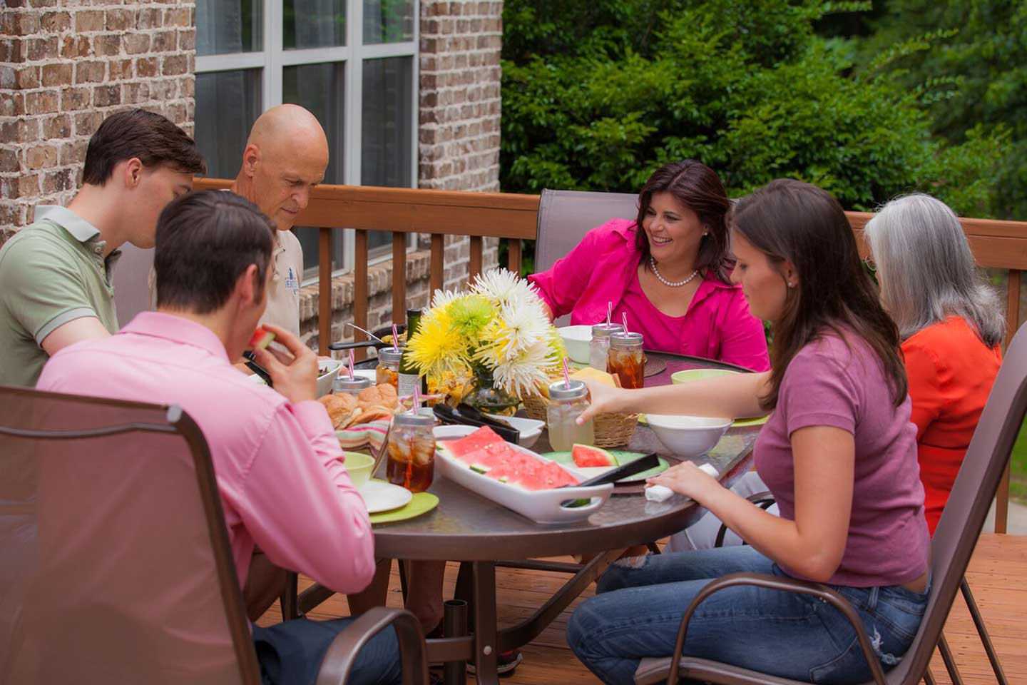 Shona Jonson and her family have a meal together on the back porch, with watermelon slices and a bouquet of flowers visible.