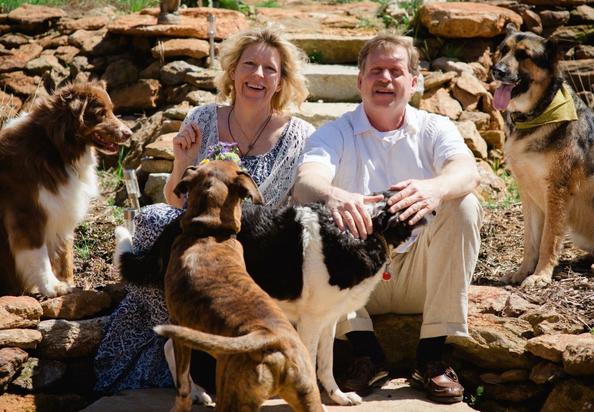 Jennifer Berry (left) and Mark Davis smile while sitting on the ground with their four dogs
