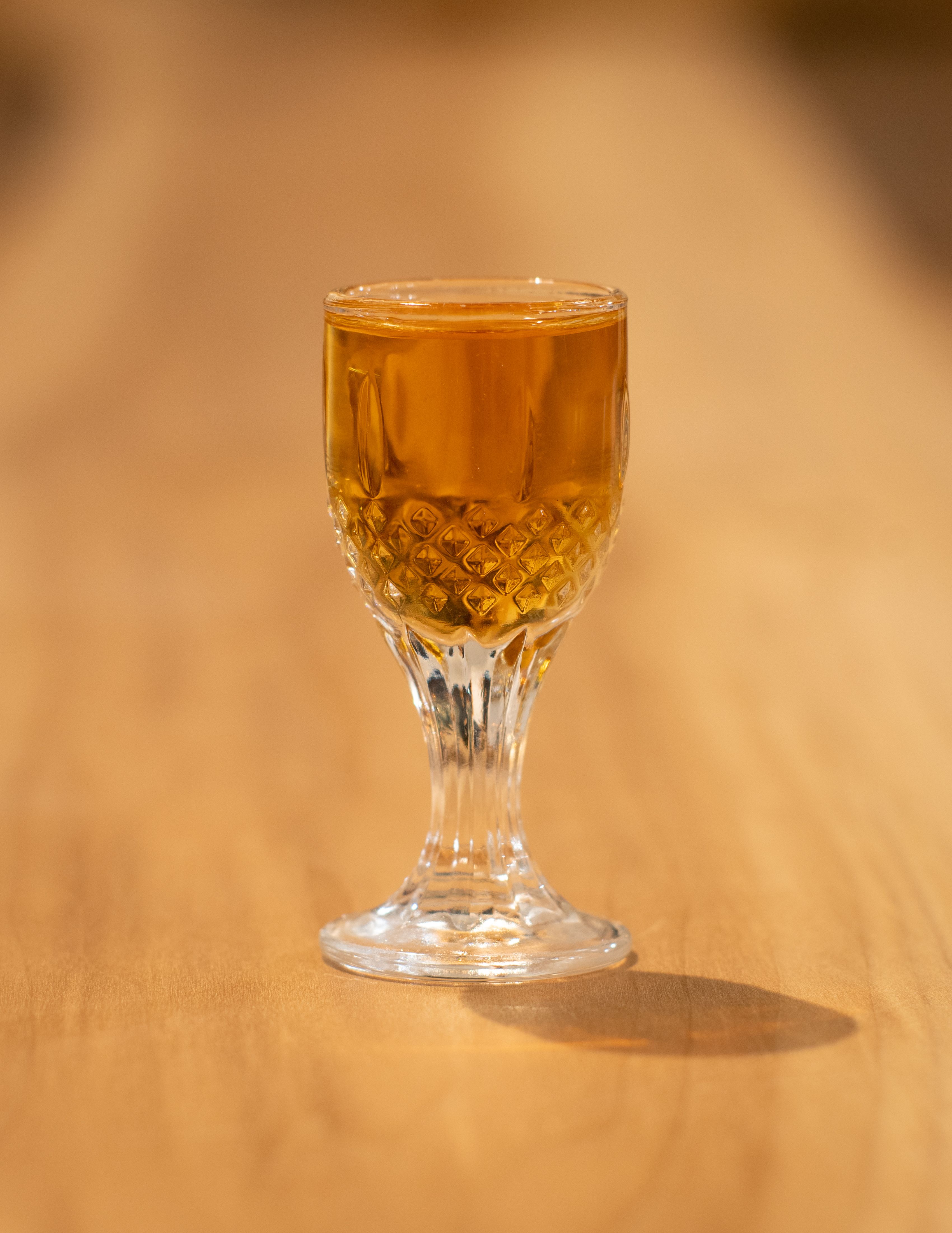 A glass of whiskey sits on a wooden bar