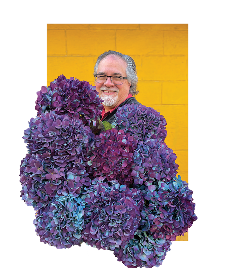 Portrait of Scott Shepherd with violet flowers in the foreground.