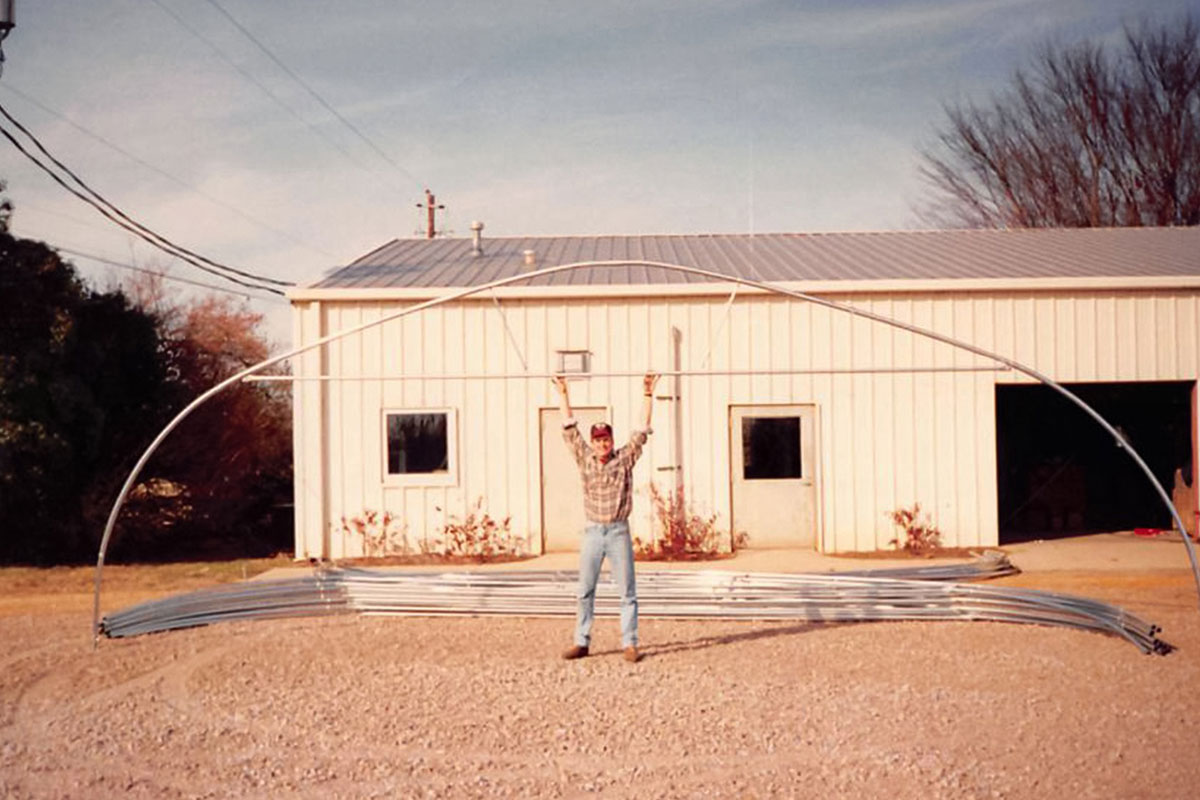 A sepia photo of a man building a greenhouse
