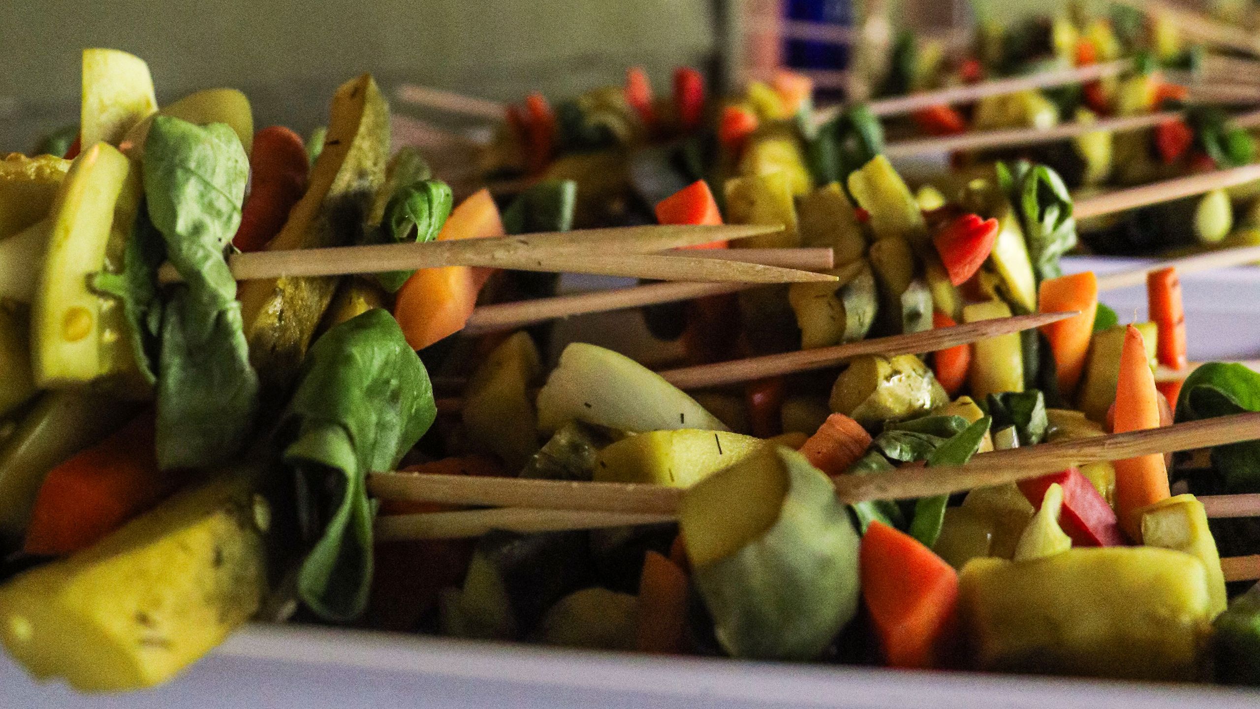 Colorful vegetable kabobs are lined up in this close up image.
