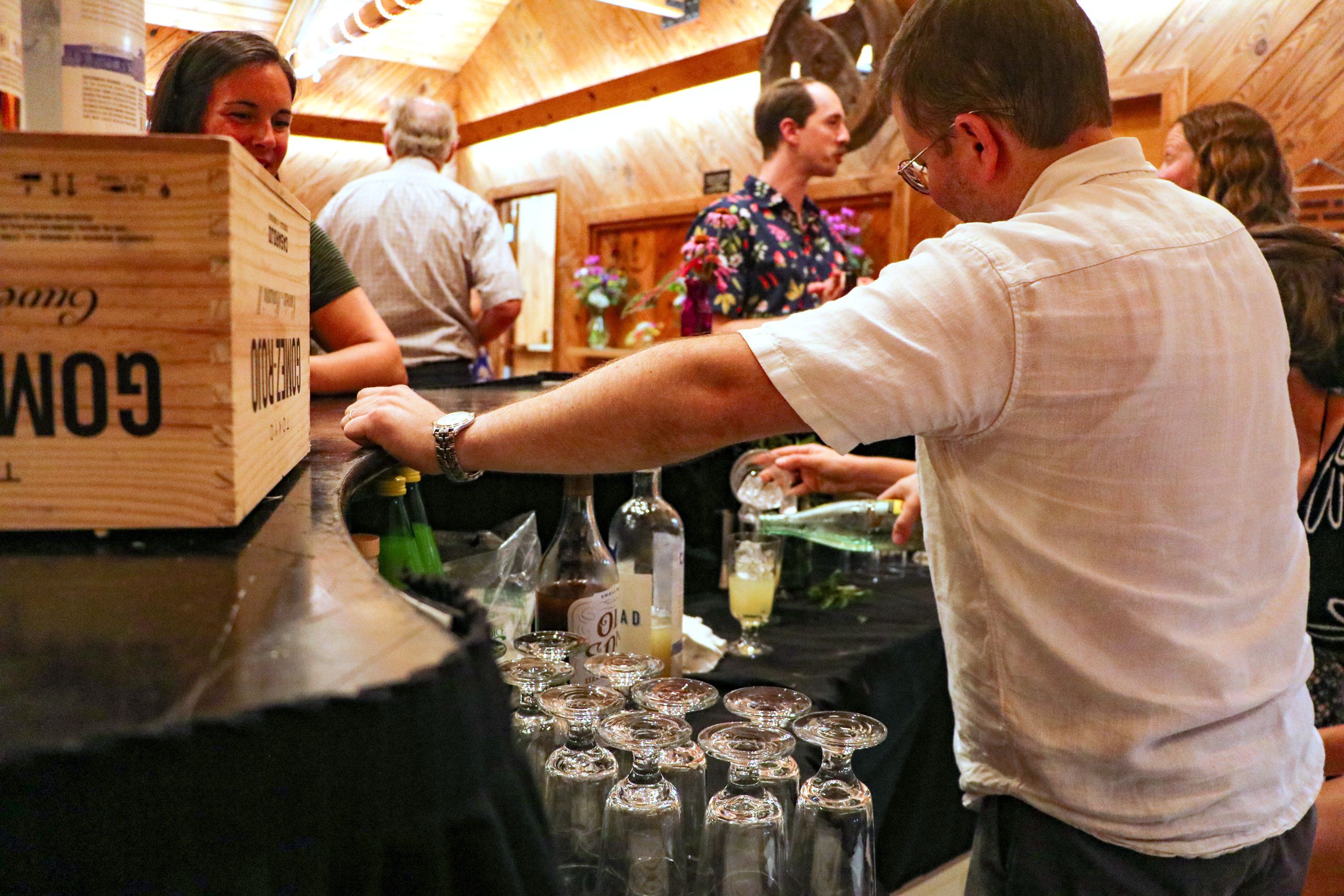 The bartender prepares drinks for guests waiting at the bar. 