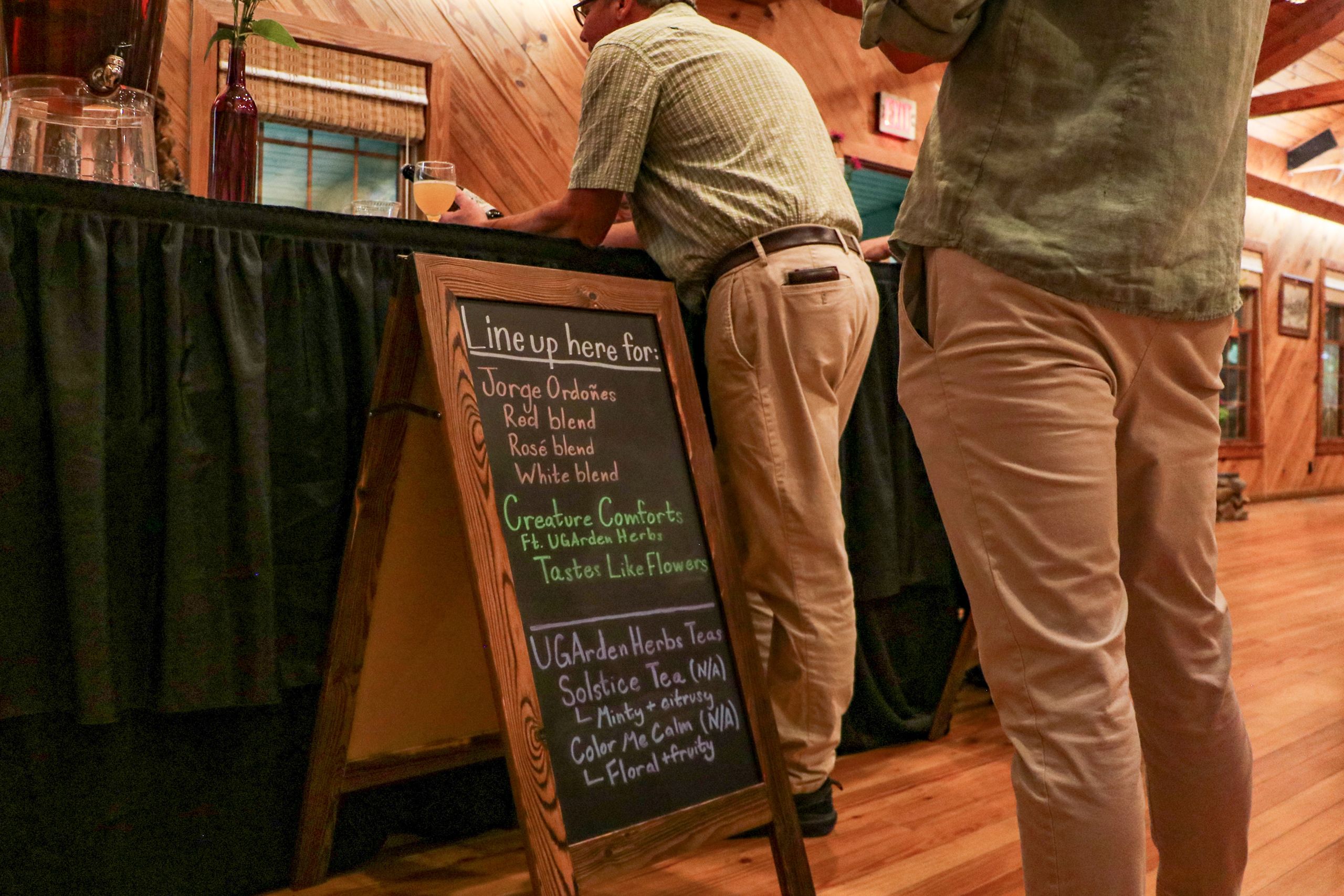 People stand in line for specialty drinks, which are listed on the sandwich board to the left of them.