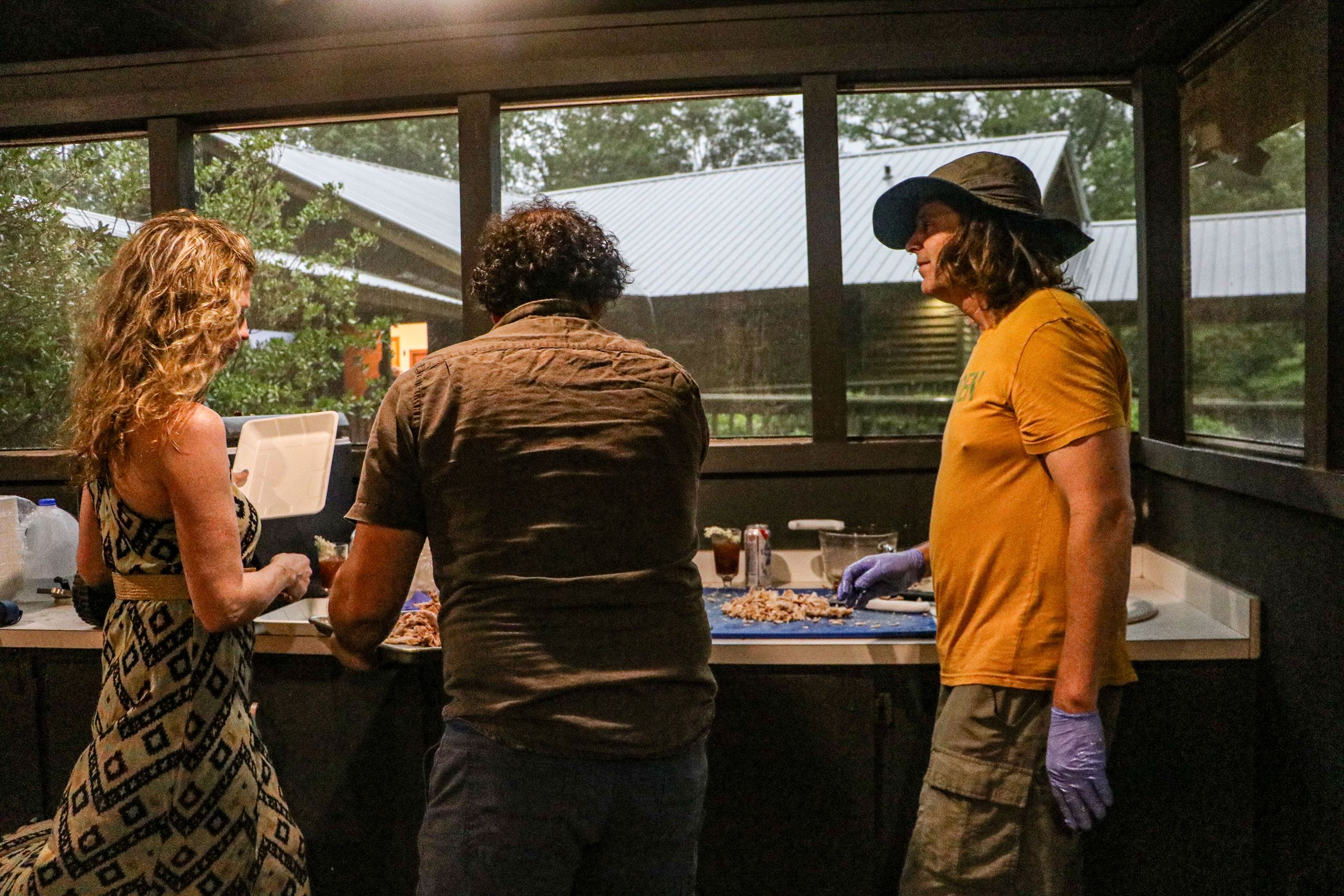 Three people work together to prepare chopped meat that will be served for dinner. 