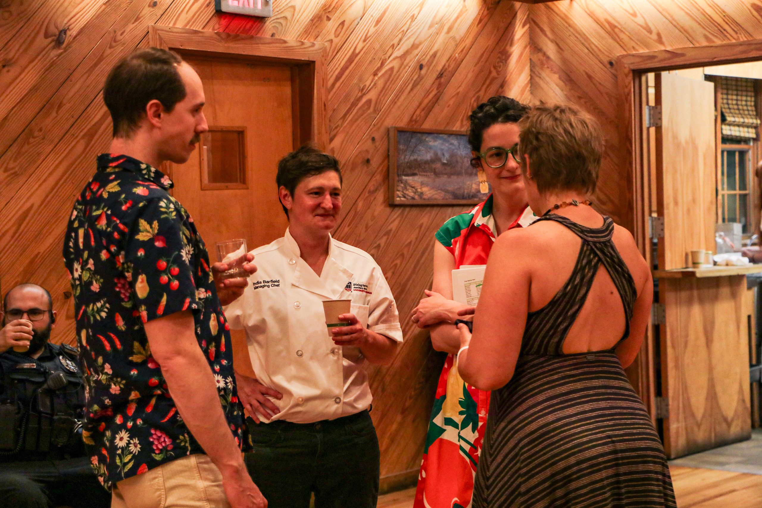 Several guests stand and talk with a chef inside the banquet hall.
