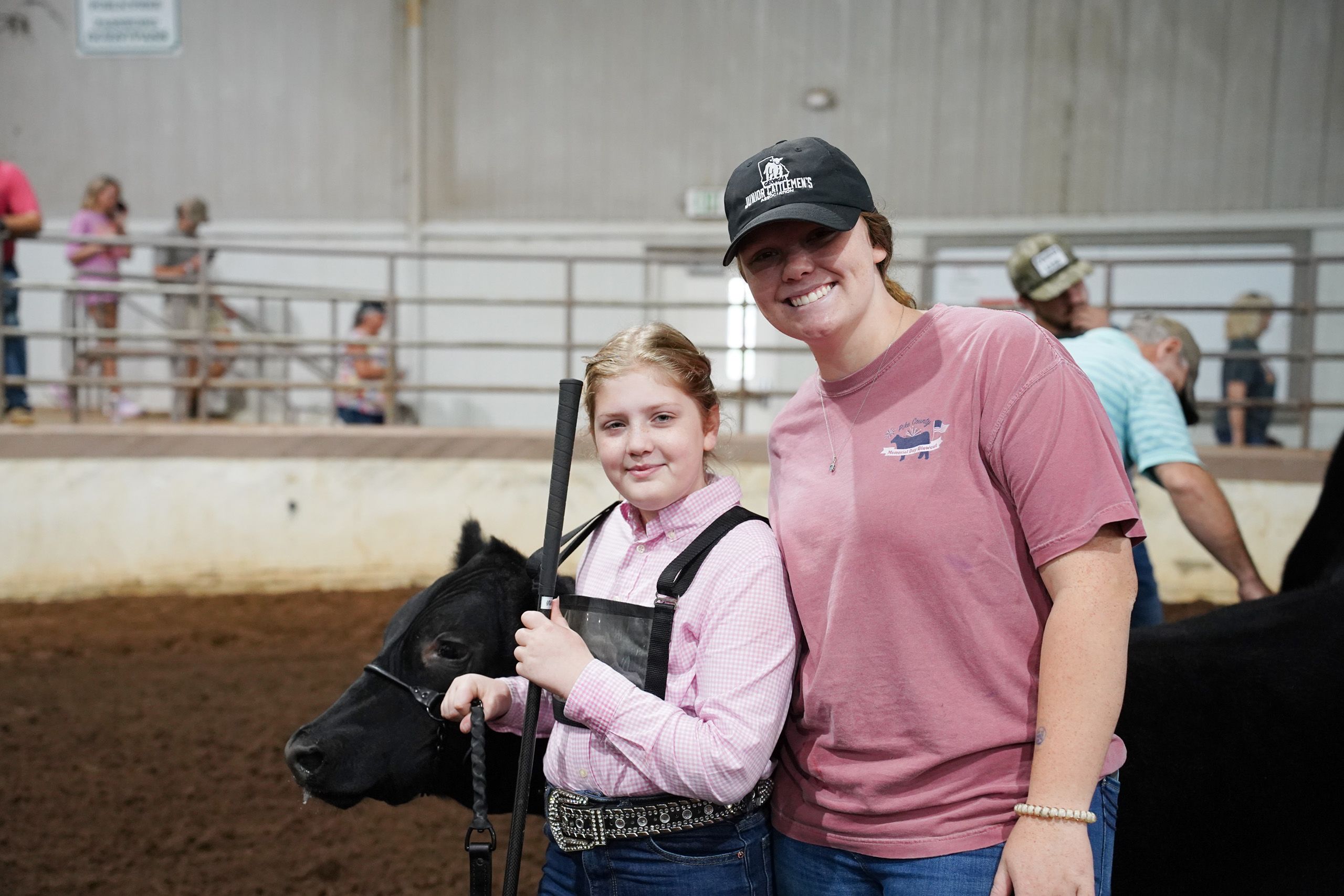 A woman and a young 4-H'er smile while holding the reins of a black cow in a show ring at the Georgia National Fair. 