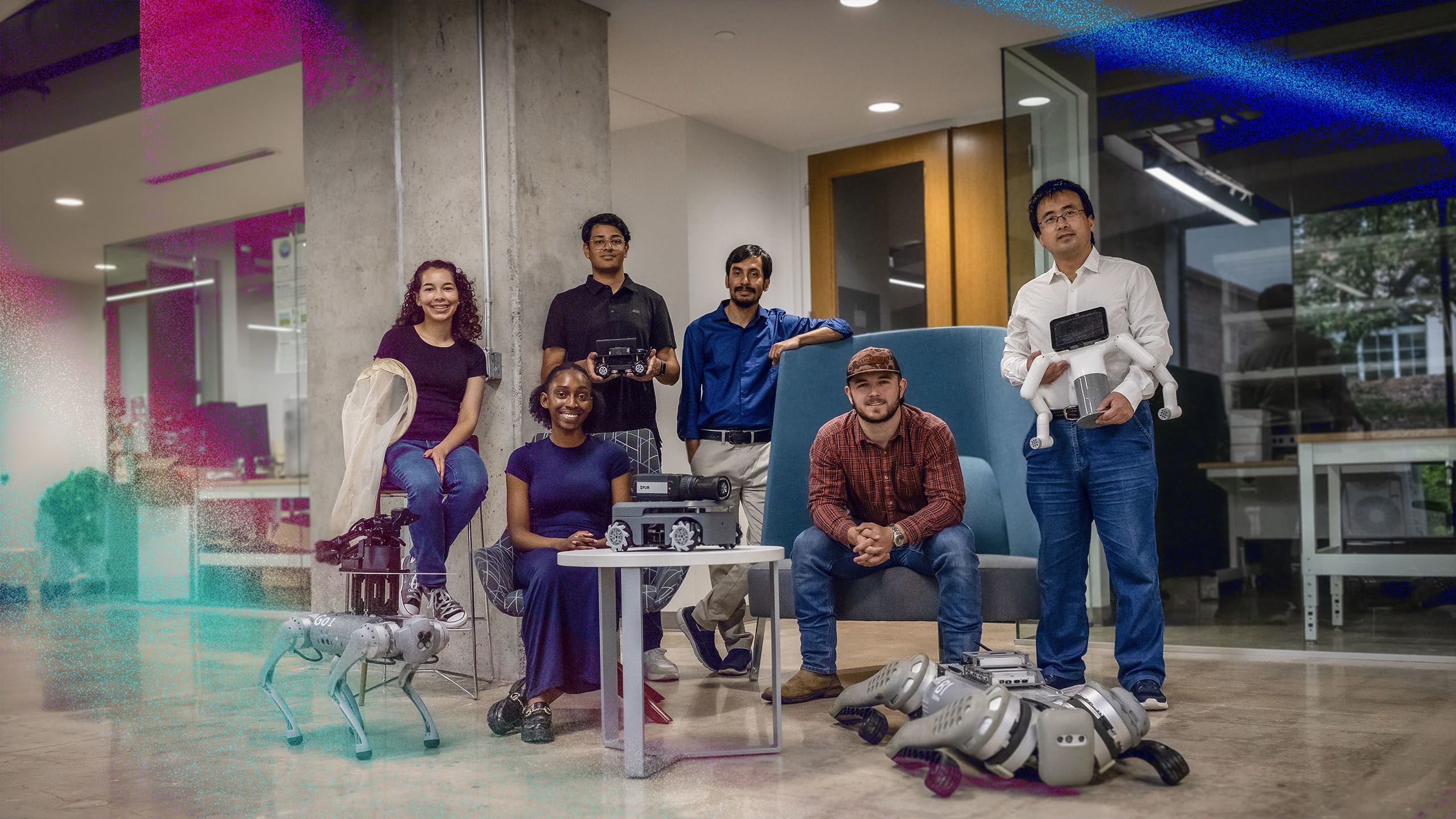 Six people posing in a modern lab space with robotics equipment, including robotic dogs and devices.