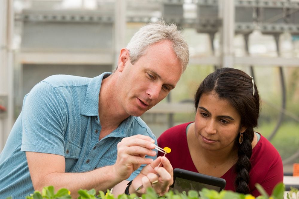 Scott Jackson works with a student in the greenhouse