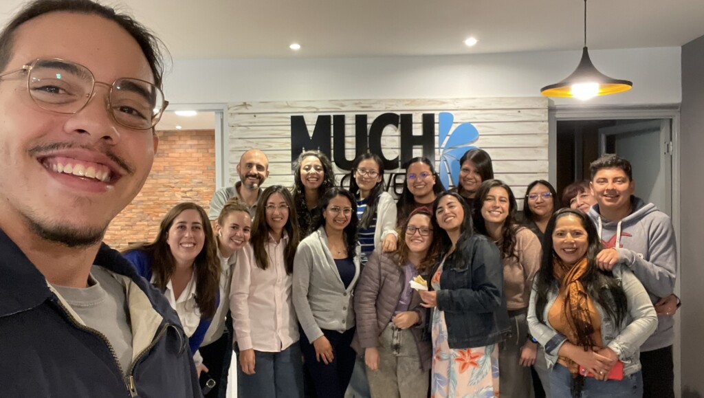 A selfie of a group of employees in front of a sign that reads Much Flowers.