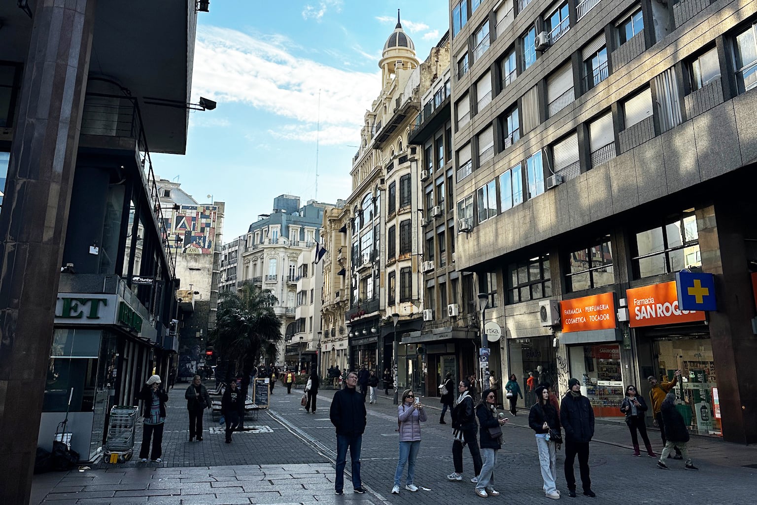 People gathering and walking down a building-lined street in Uruguay