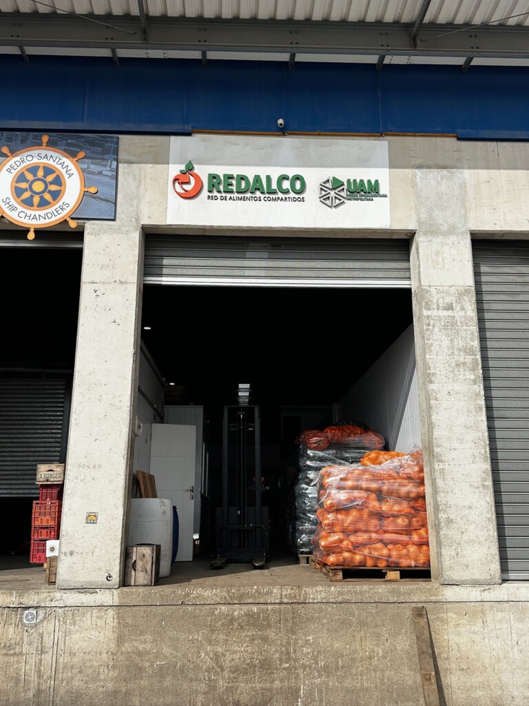 A medium angle photo of a delivery dock door with pallets of produce inside and REDALCO on a sign above the door.