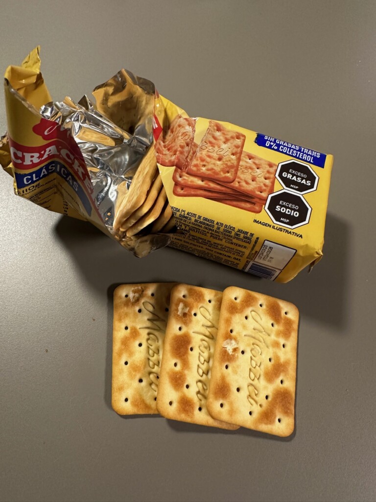 An open package of crackers on a table with three crackers laid out below the package.