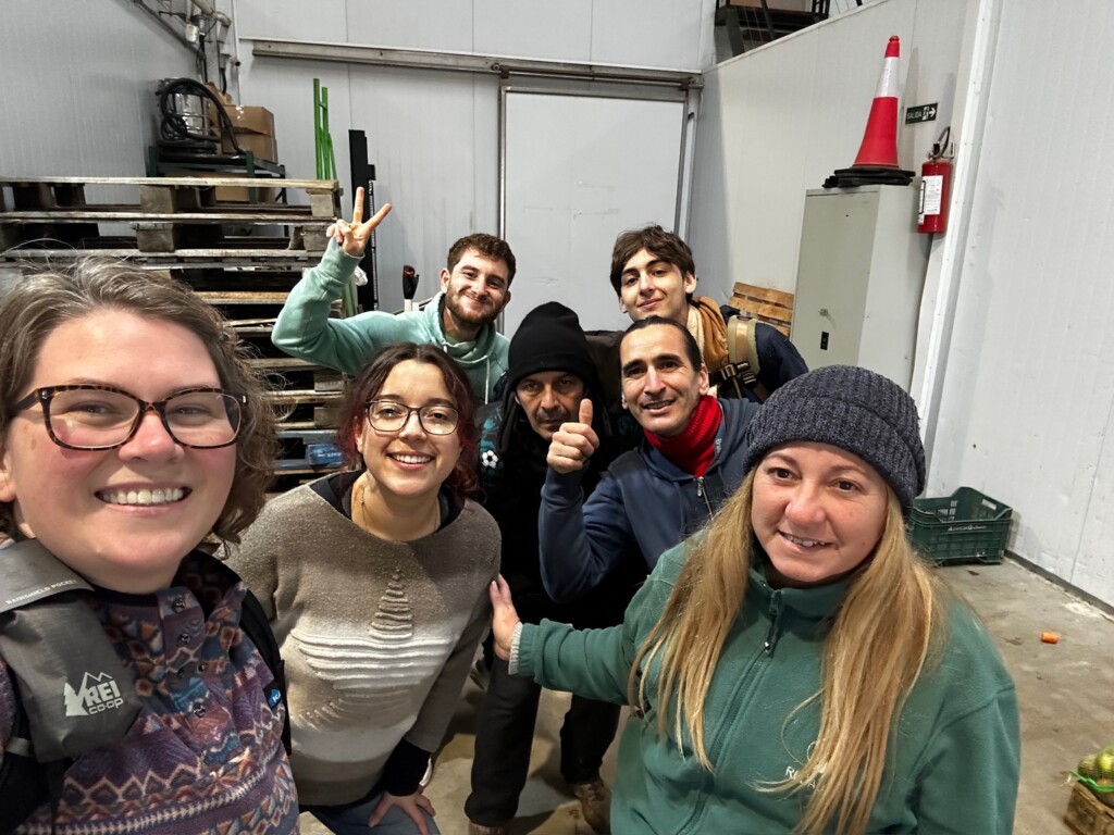 A selfie of a group of people indoors in a factory setting.