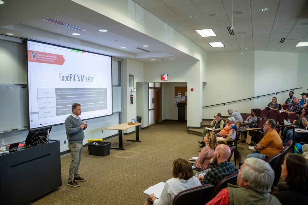 James Gratzek of UGA's Food Product, Innovation, and Commercialization Center (FoodPIC). A projected slide reads "FoodPIC's Mission" behind him.