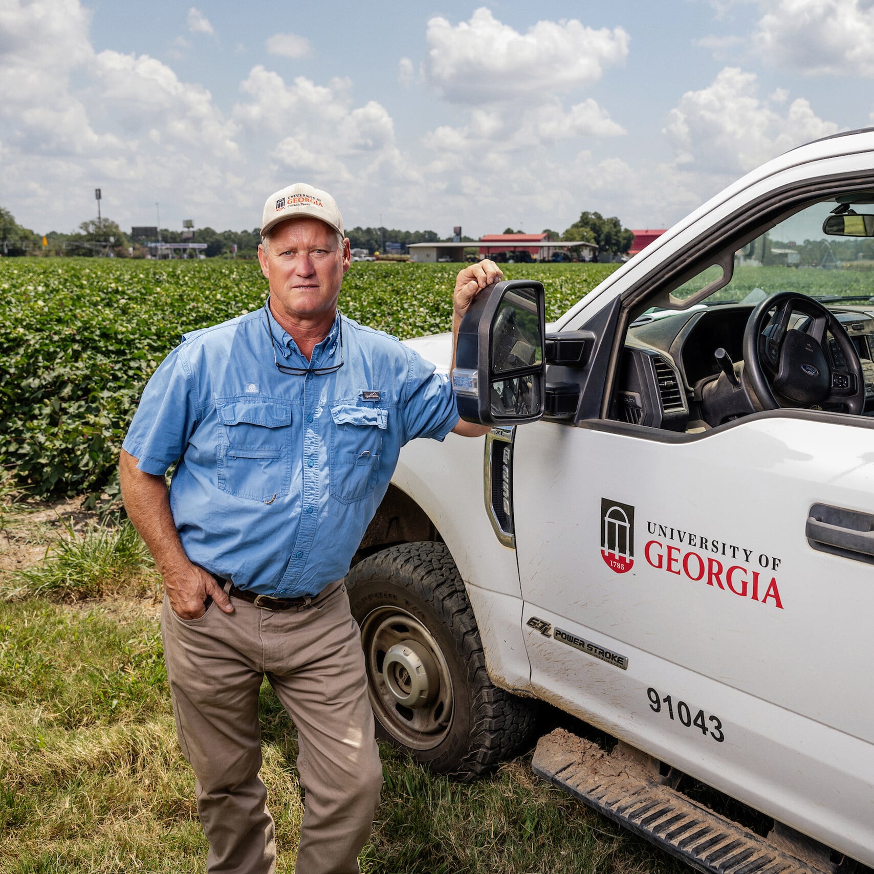 Phillip Roberts stands beside a UGA truck in a cotton field
