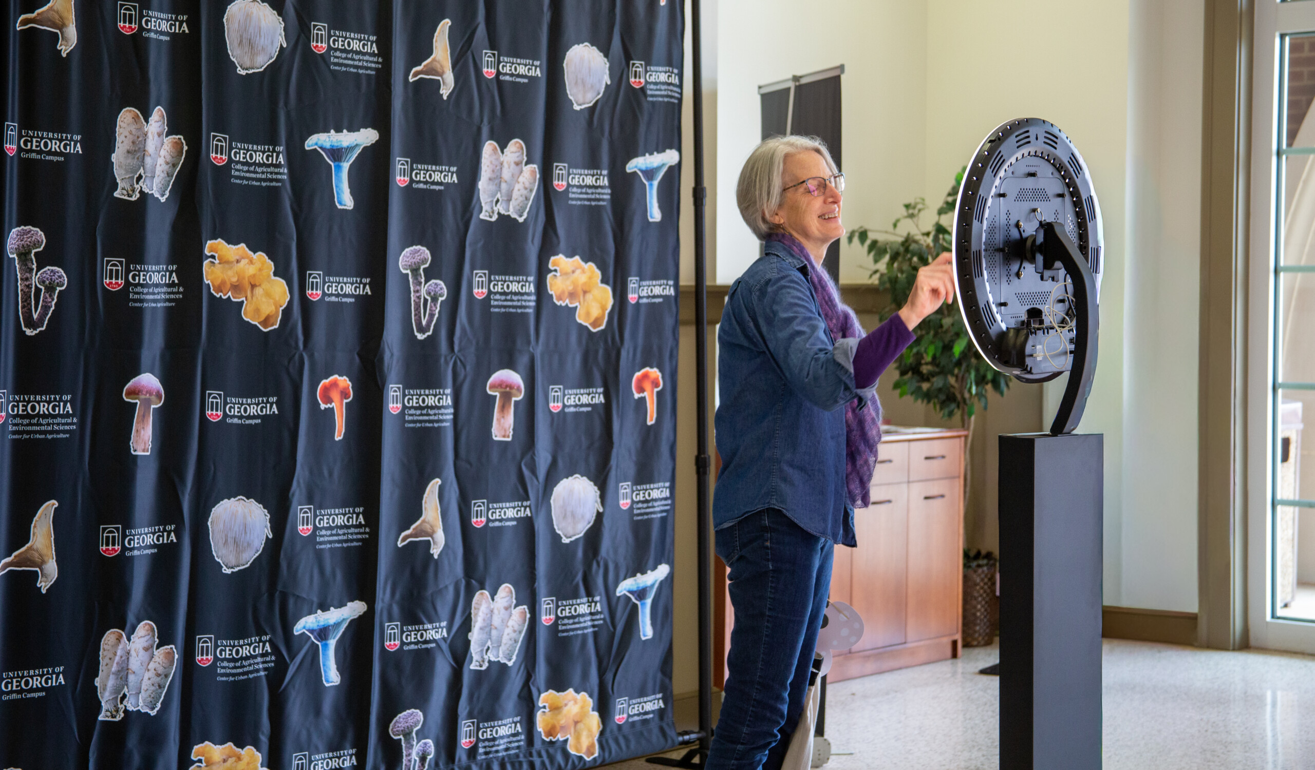 An attendee uses the camera set up in front of the mushroom themed photo backdrop.