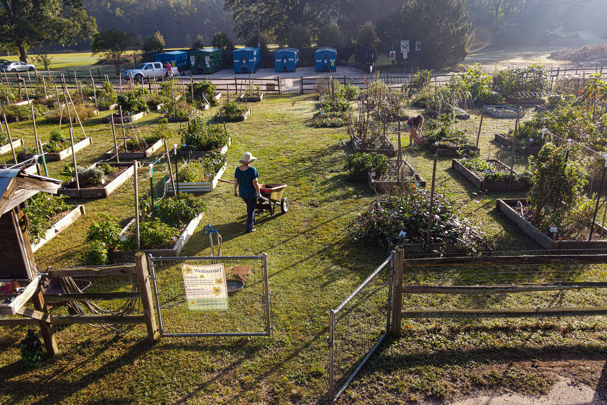 The community garden in Winterville, Georgia, with someone pushing a wheelbarrow at center