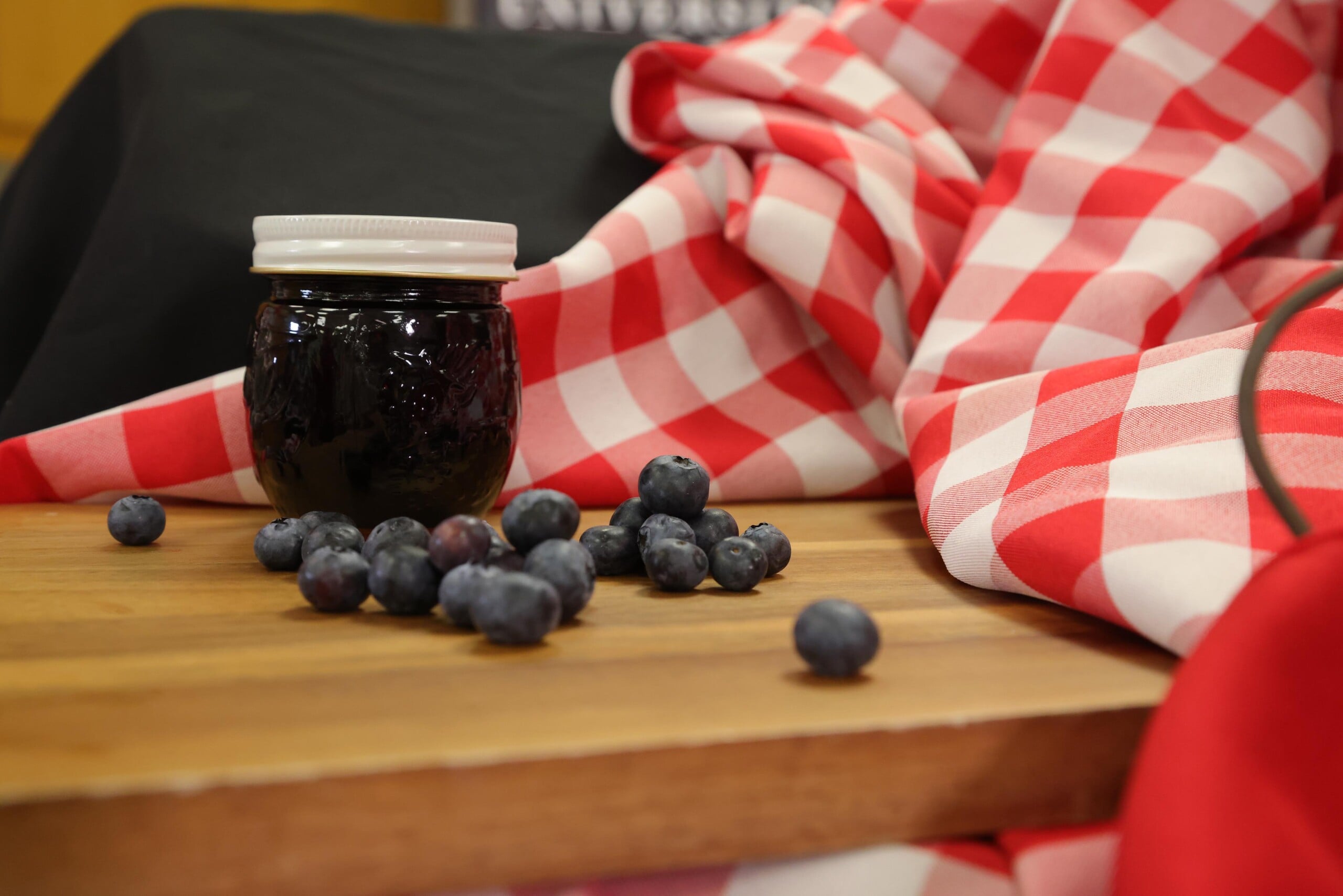 Jar of blueberry jam with fresh blueberries on a counter